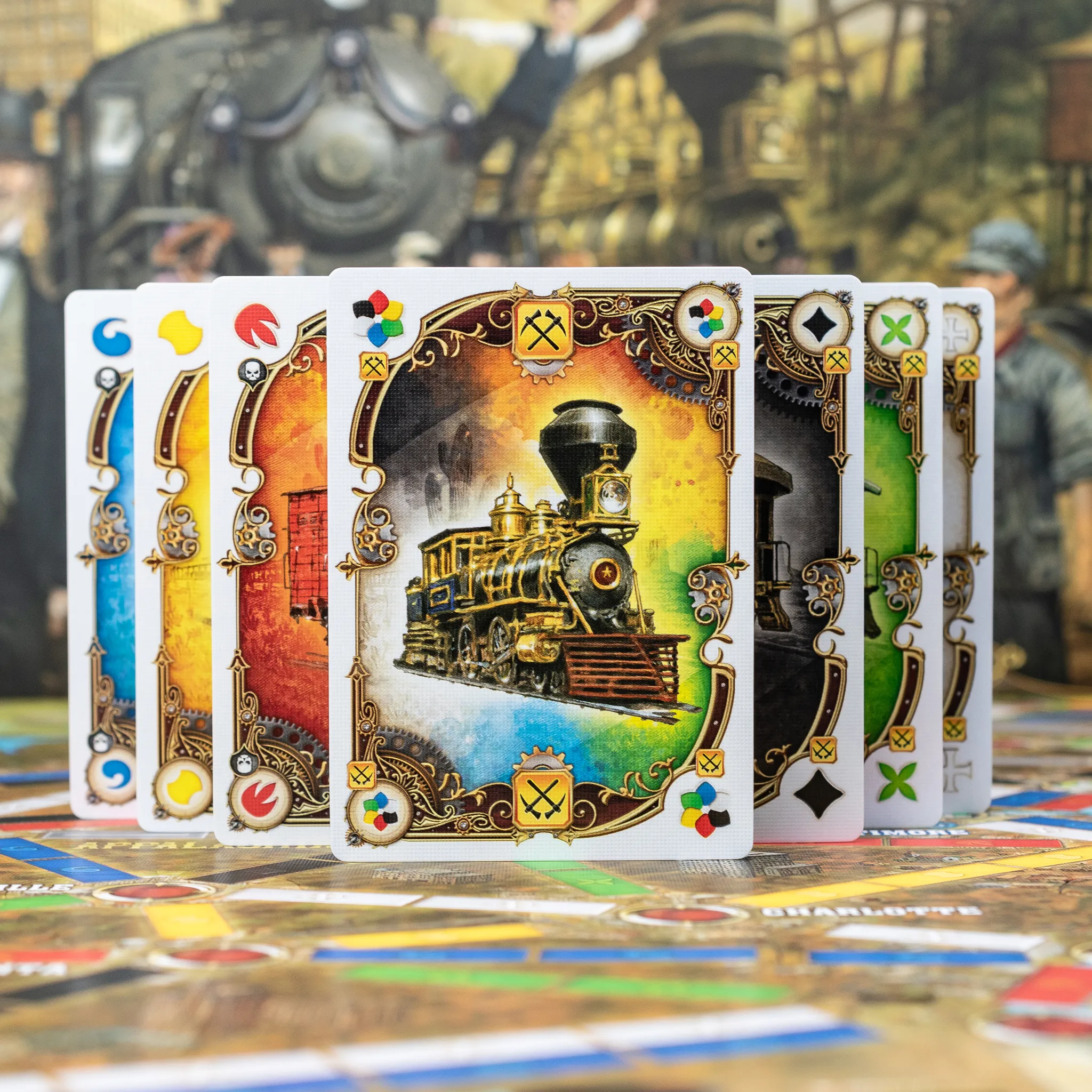 A fanned out set of colorful playing cards with a train illustration, set against a blurred outdoor background.