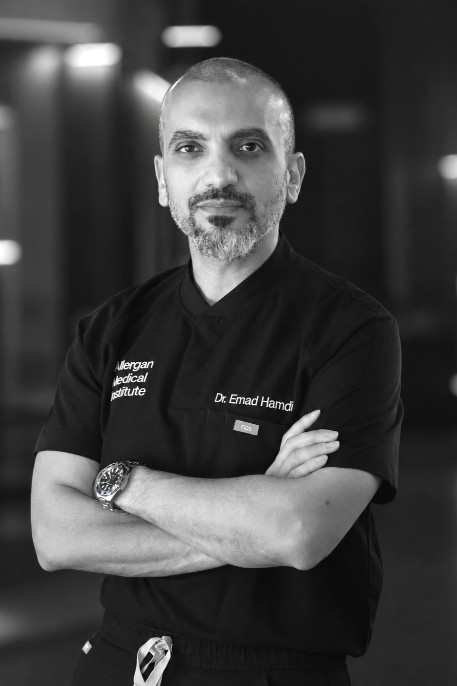 Black and white portrait of Dr. Emad Hamdi from Allergan Medical Institute, wearing medical scrubs with arms crossed, standing in a professional setting.
