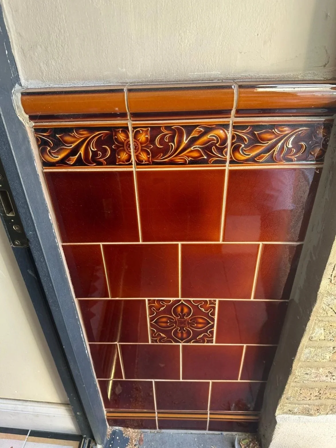 Close-up of decorative brown ceramic tiles with floral patterns on a wall or panel.