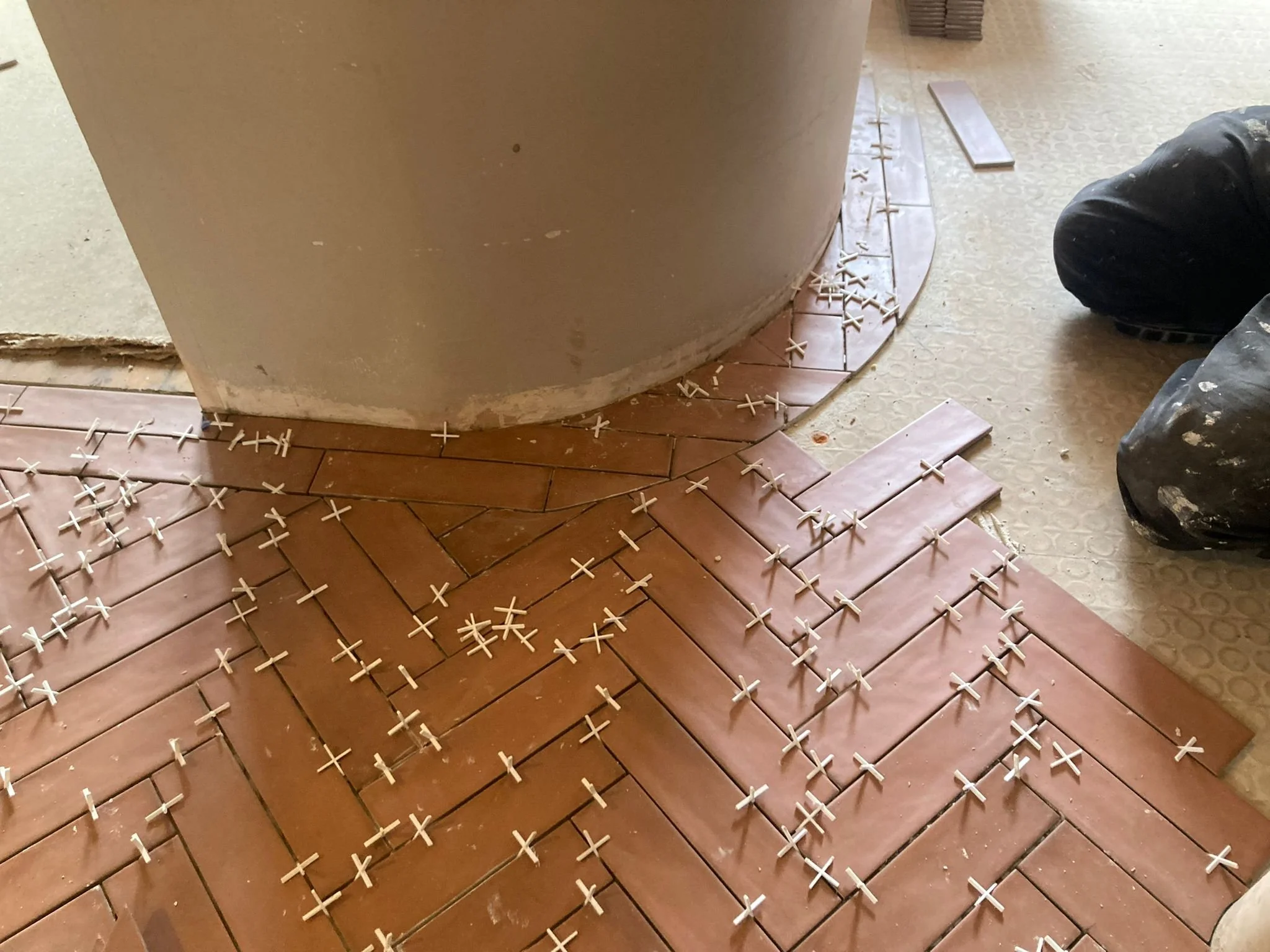 Flooring tiles in the process of being installed, with spacers arranged between the tiles for grouting.