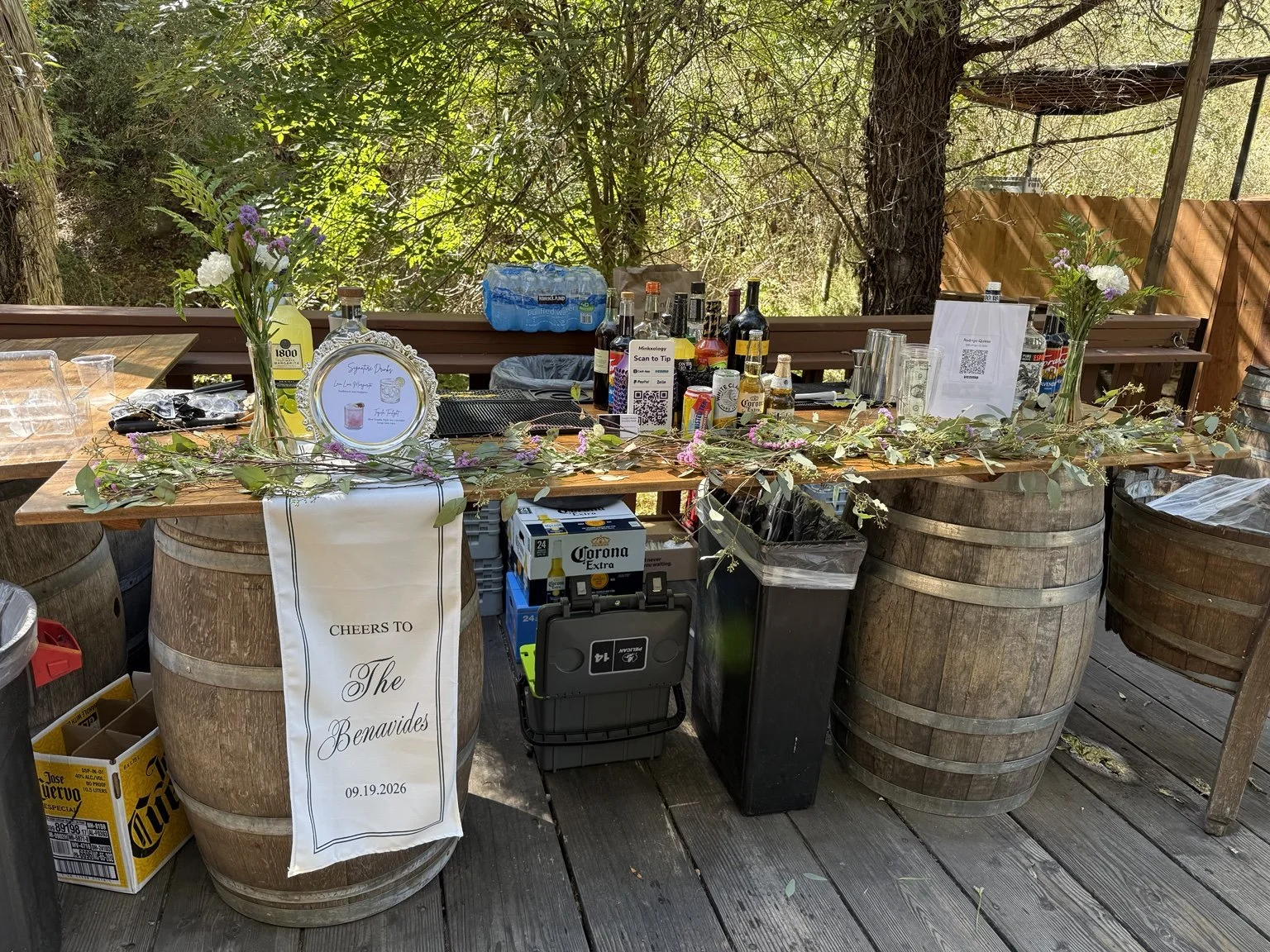 Outdoor bar setup from wedding event with floral garland and decorated beverage dispensers