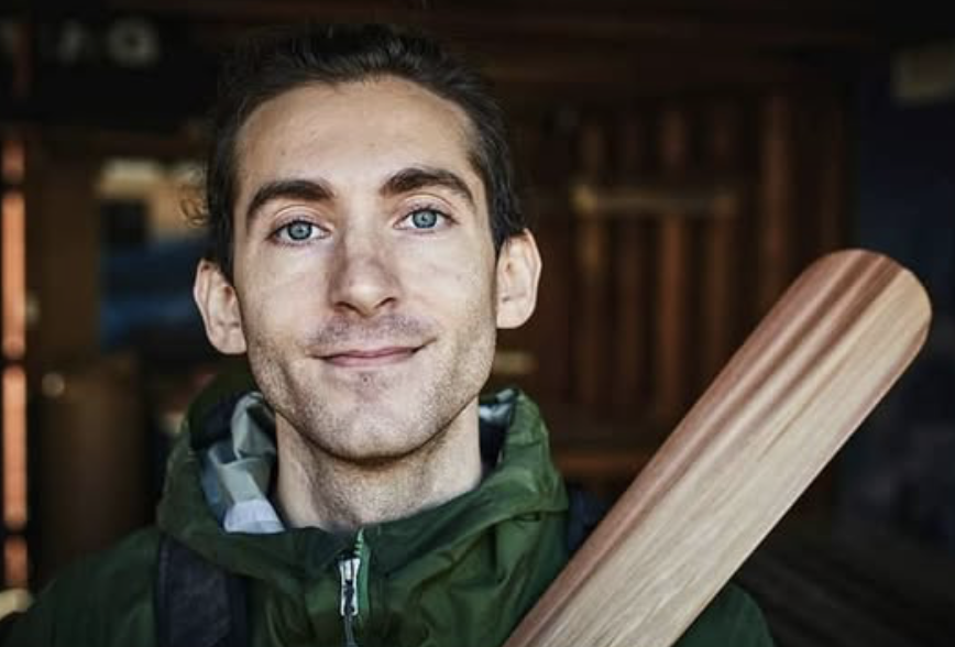 Young man with blue eyes and dark hair holding Western Red Cedar Traditional Greenland Paddle
