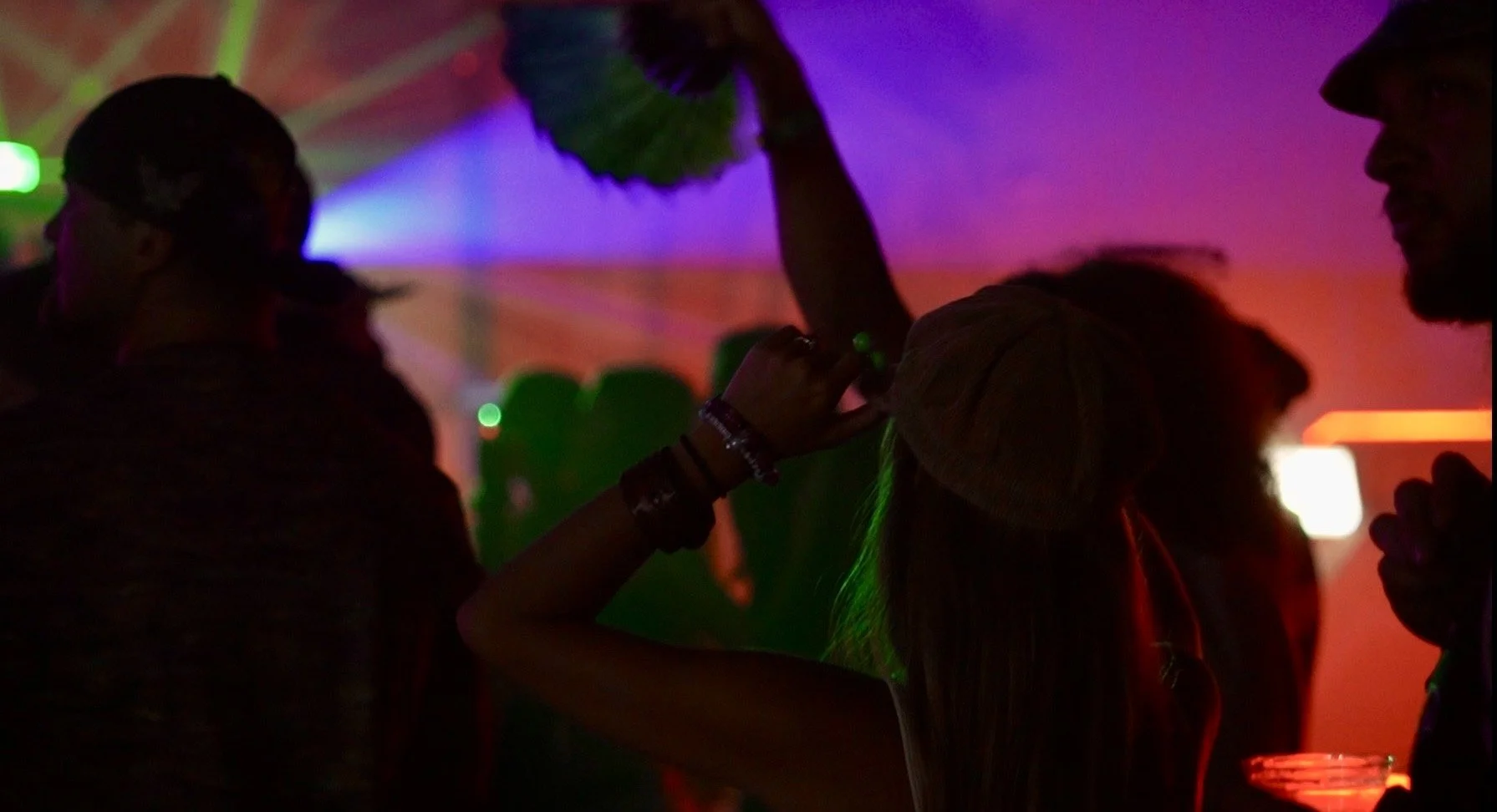 People dancing and socializing at a party with colorful lights.