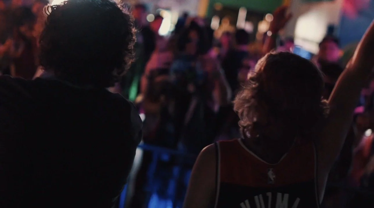 People dancing at a crowded dance party or club with colorful lighting.