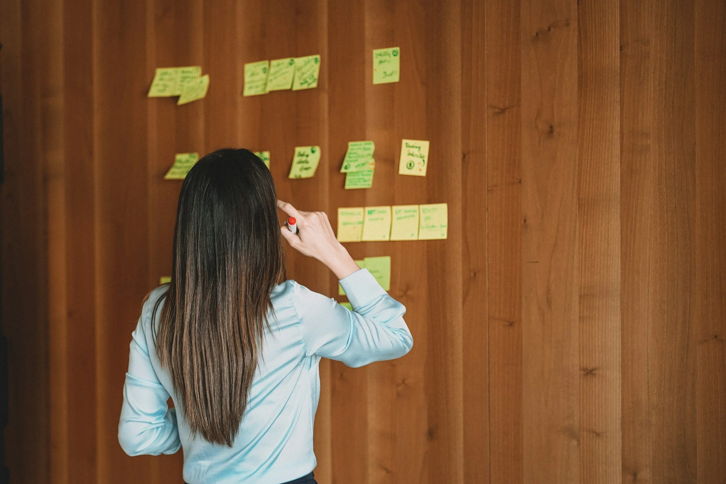 professional woman stands in front of board with post-it notes