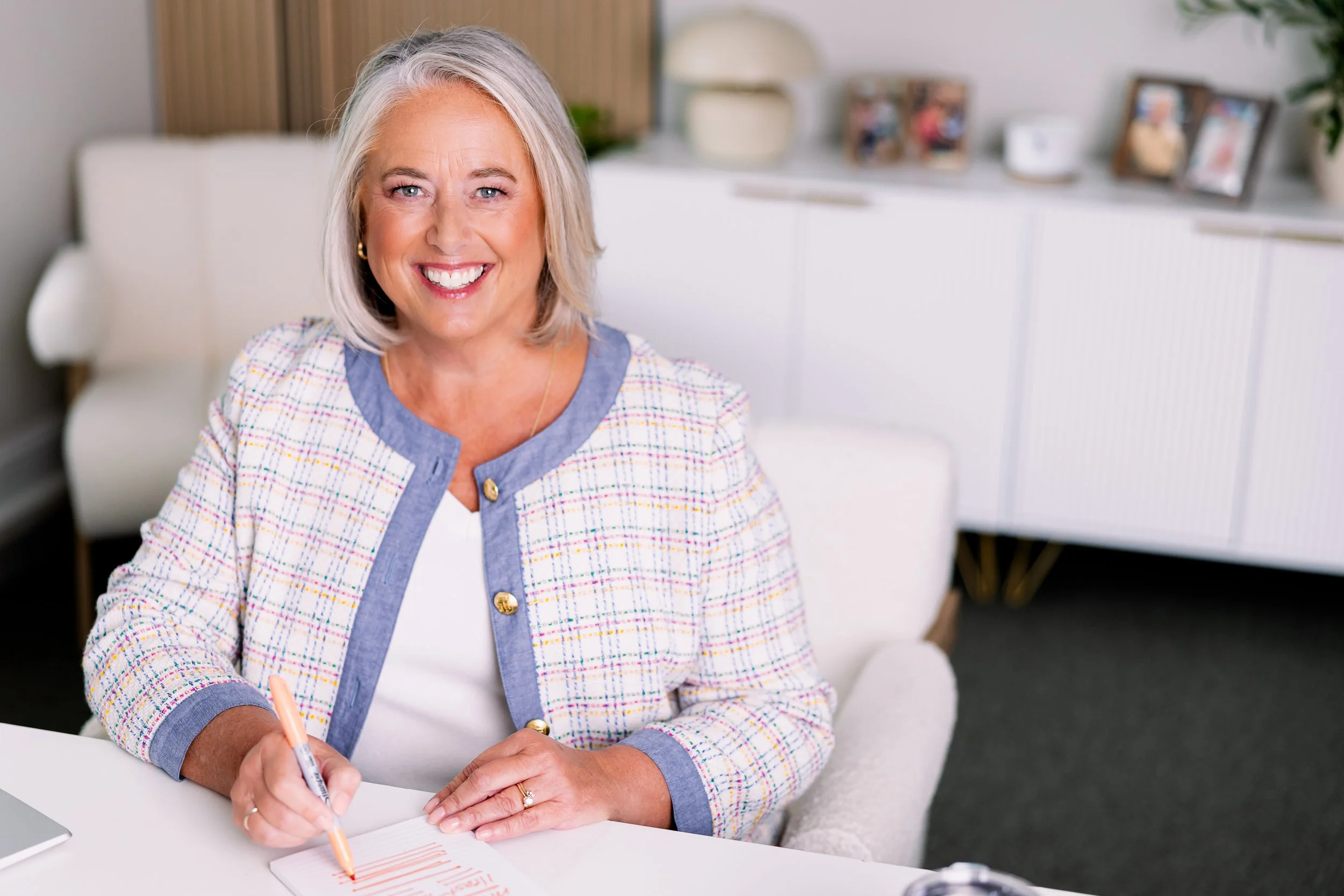 professional headshot of Angie Karesh, founder of Peak Leadership Coaching, writing at her desk and smiling