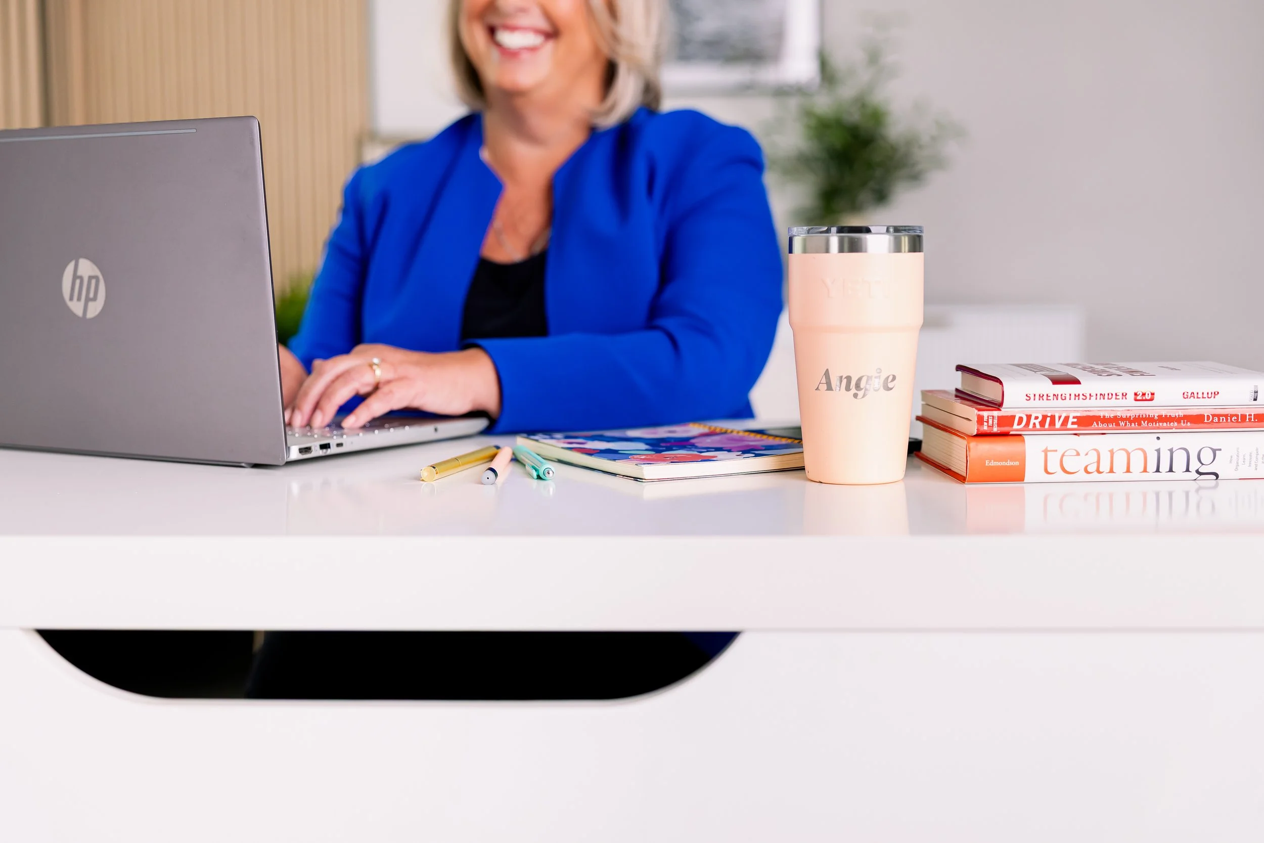 Angie Karesh, founder of Peak Leadership Coaching, typing on her computer