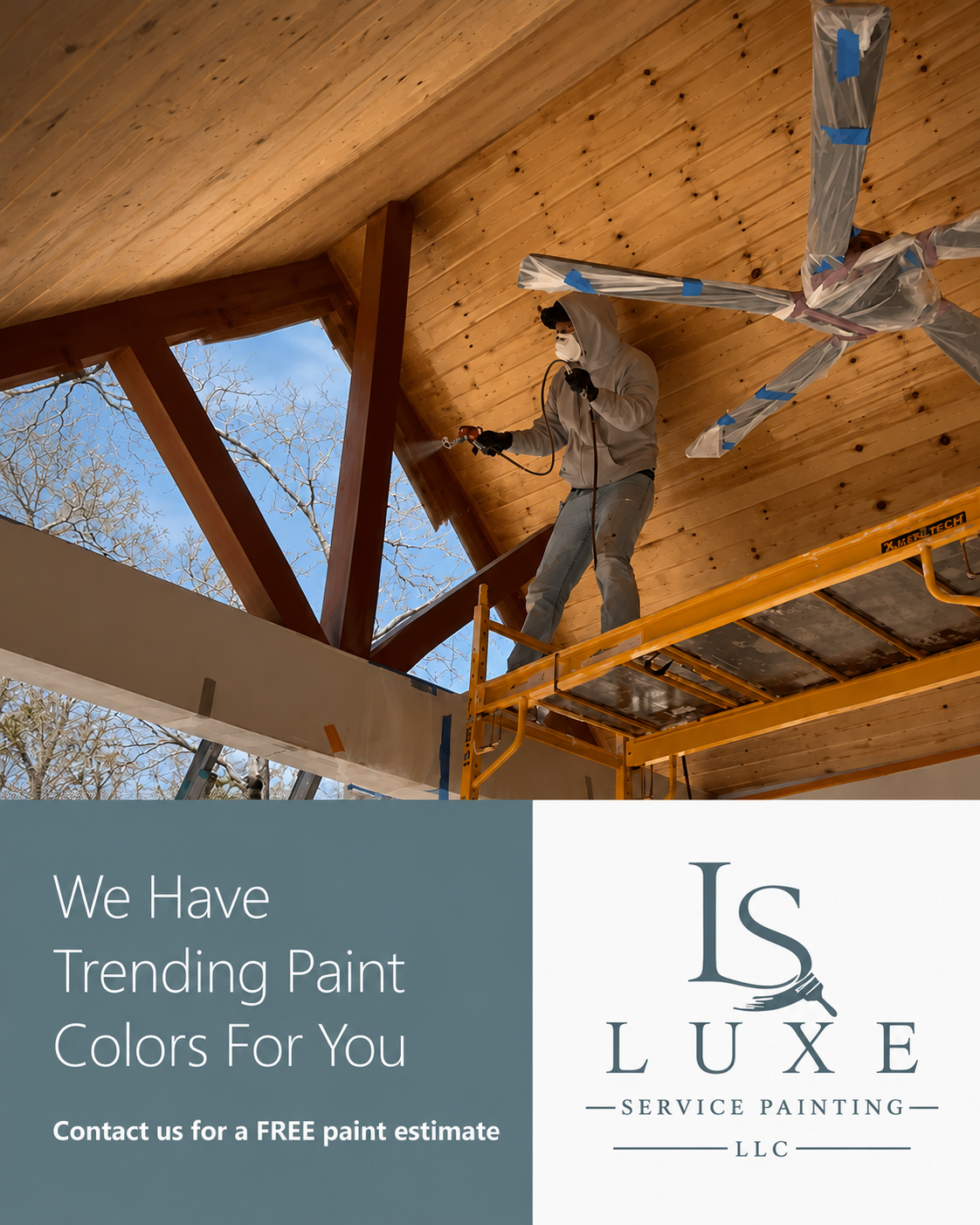 A person wearing a mask and protective clothing is standing on a scaffold, spray painting the wooden ceiling of a house interior. The ceiling has a natural wood finish, and the person appears to be applying a coat of paint or sealant.