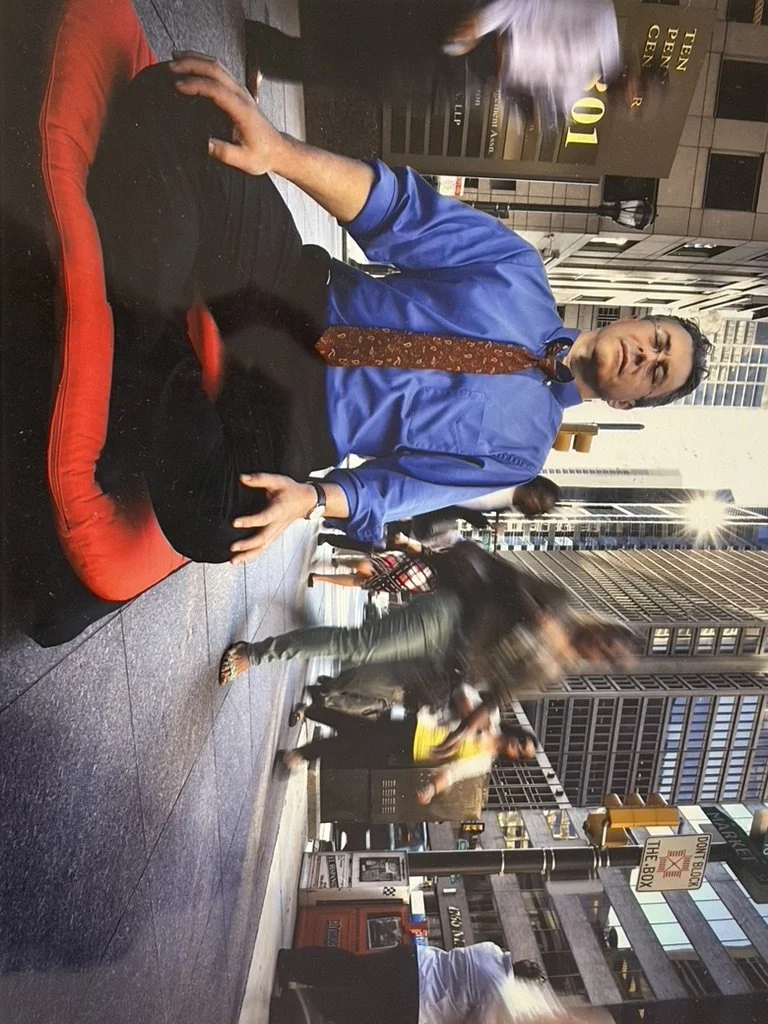 Dr. Michael Baime meditating on a red cushion on a busy city sidewalk