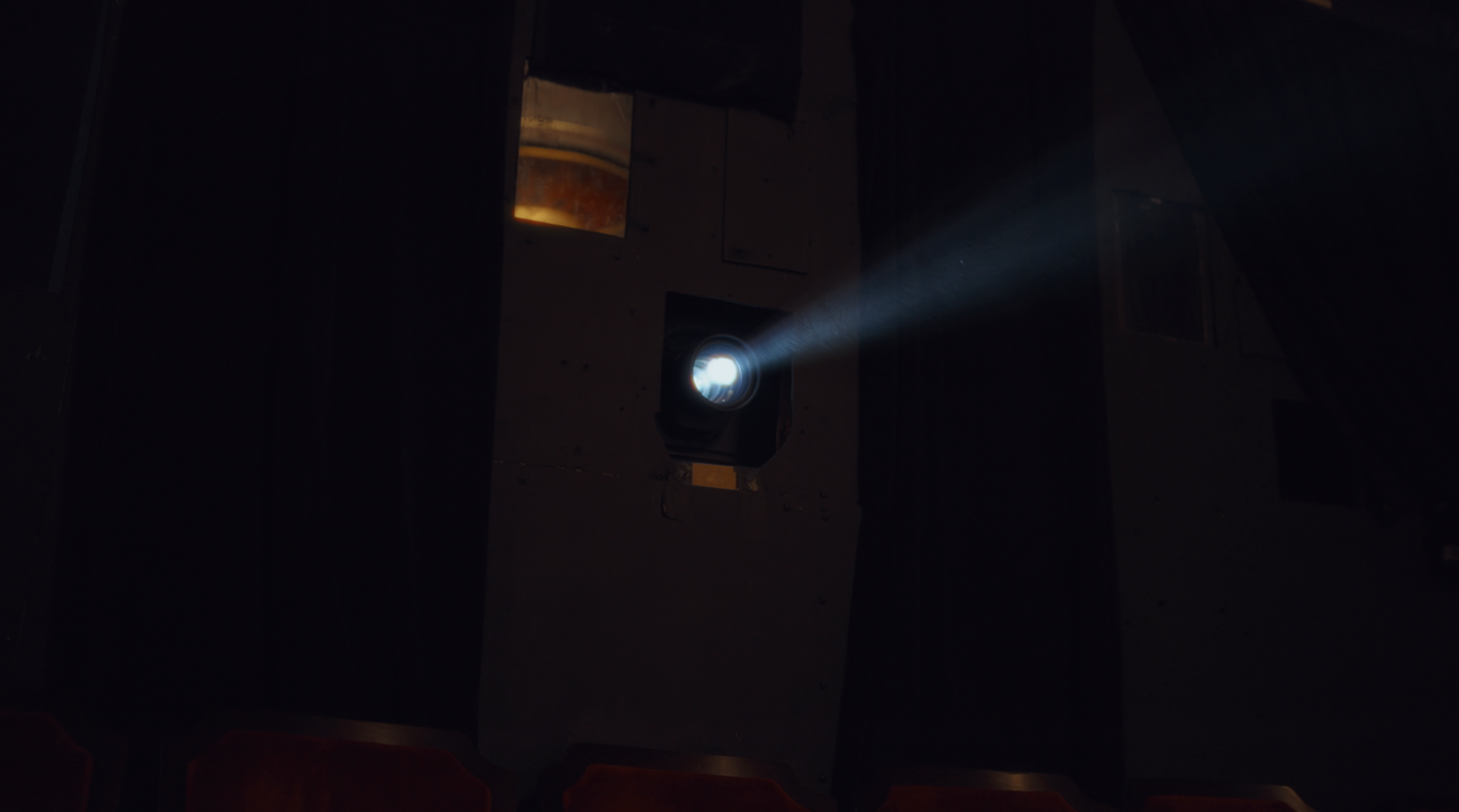 A projector on a stand casting a bright beam of light into a dark room.