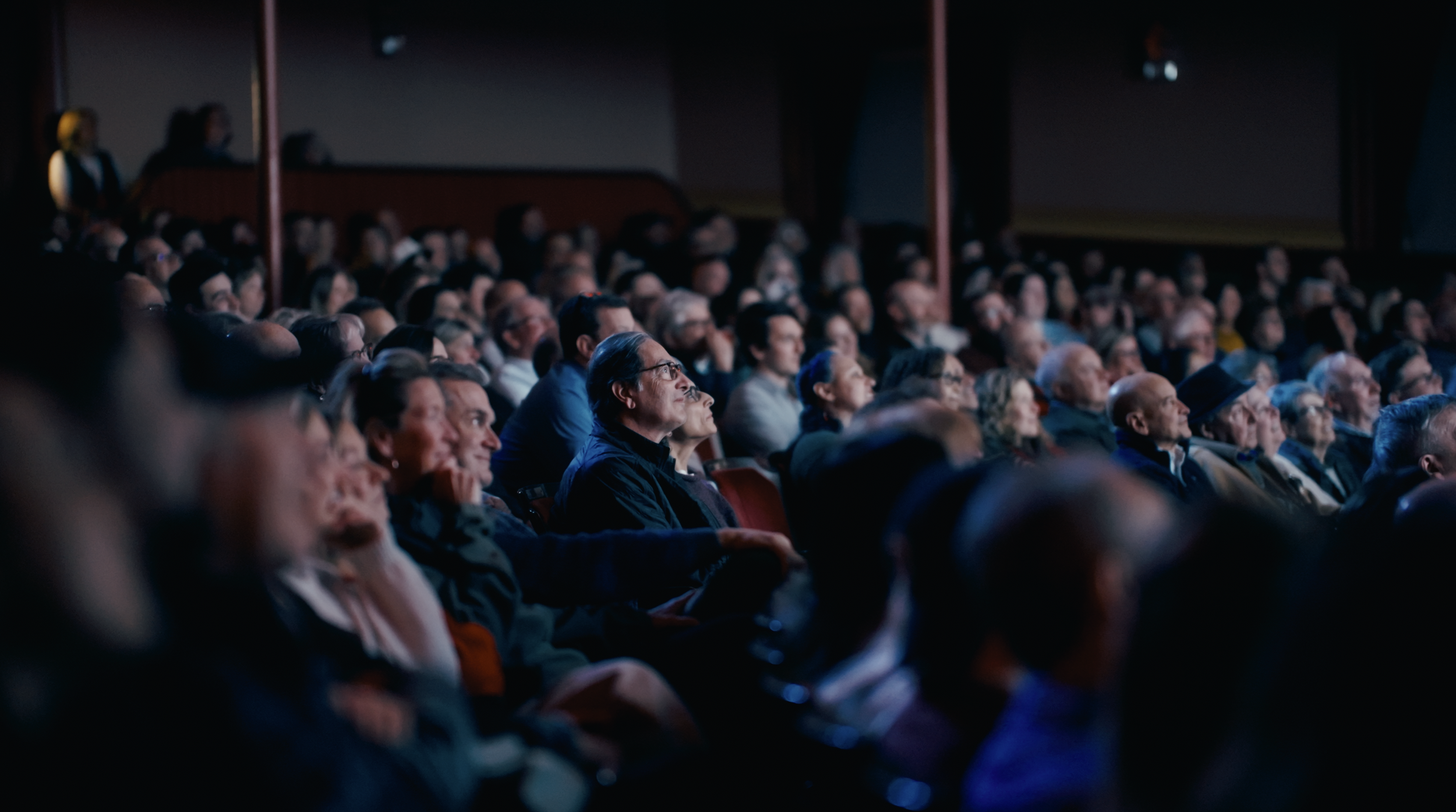 An audience sitting in a dark theater watching a presentation or movie.