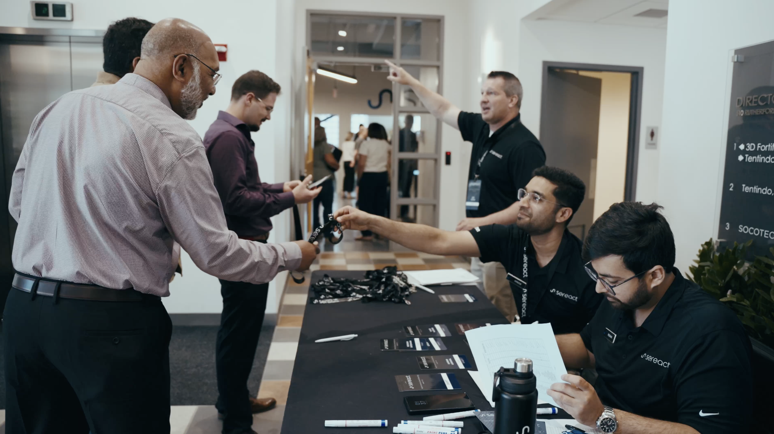 People at a registration table at a conference, with staff handing out name tags.