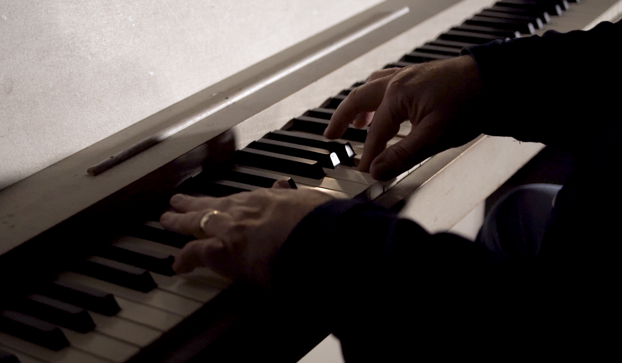 Close-up of a person's hands playing a white piano keyboard.