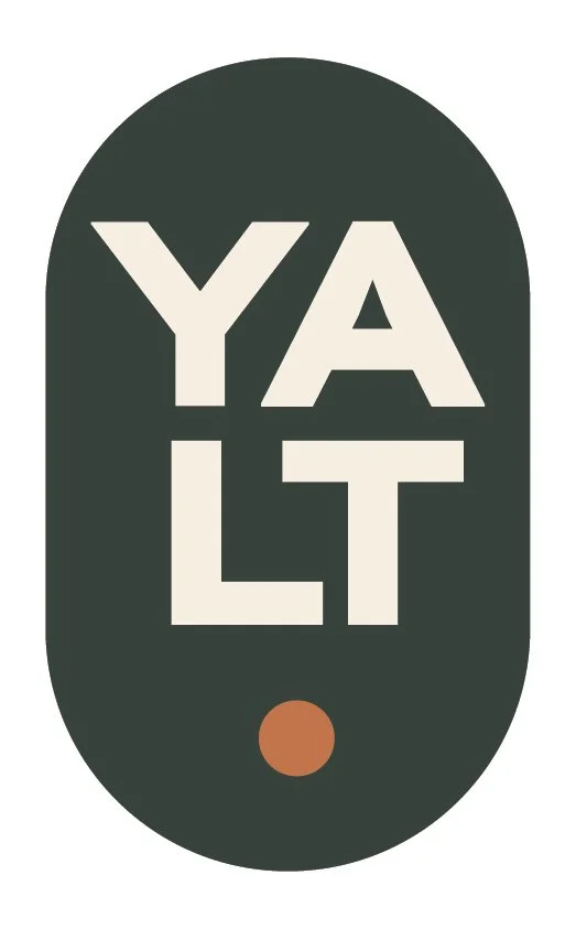 Stylized graphic design with the word "YALT" arranged vertically inside an oval shape, with a small brown circle below.
