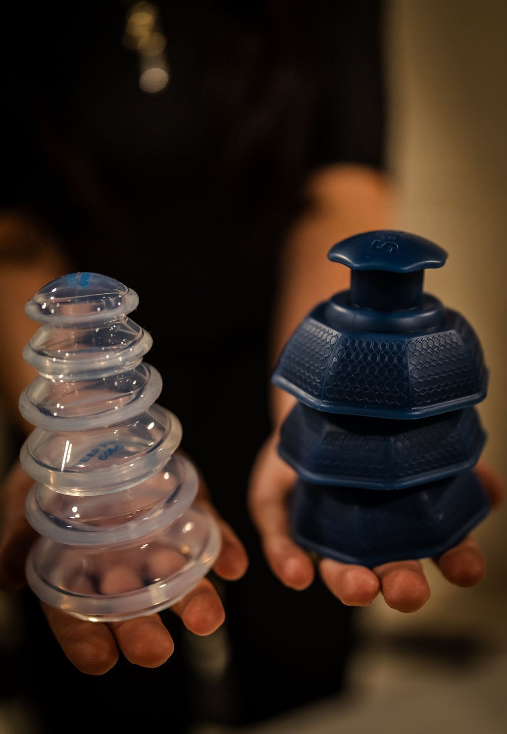 Person holding two stacks of ice packs, one clear and the other blue, in each hand.