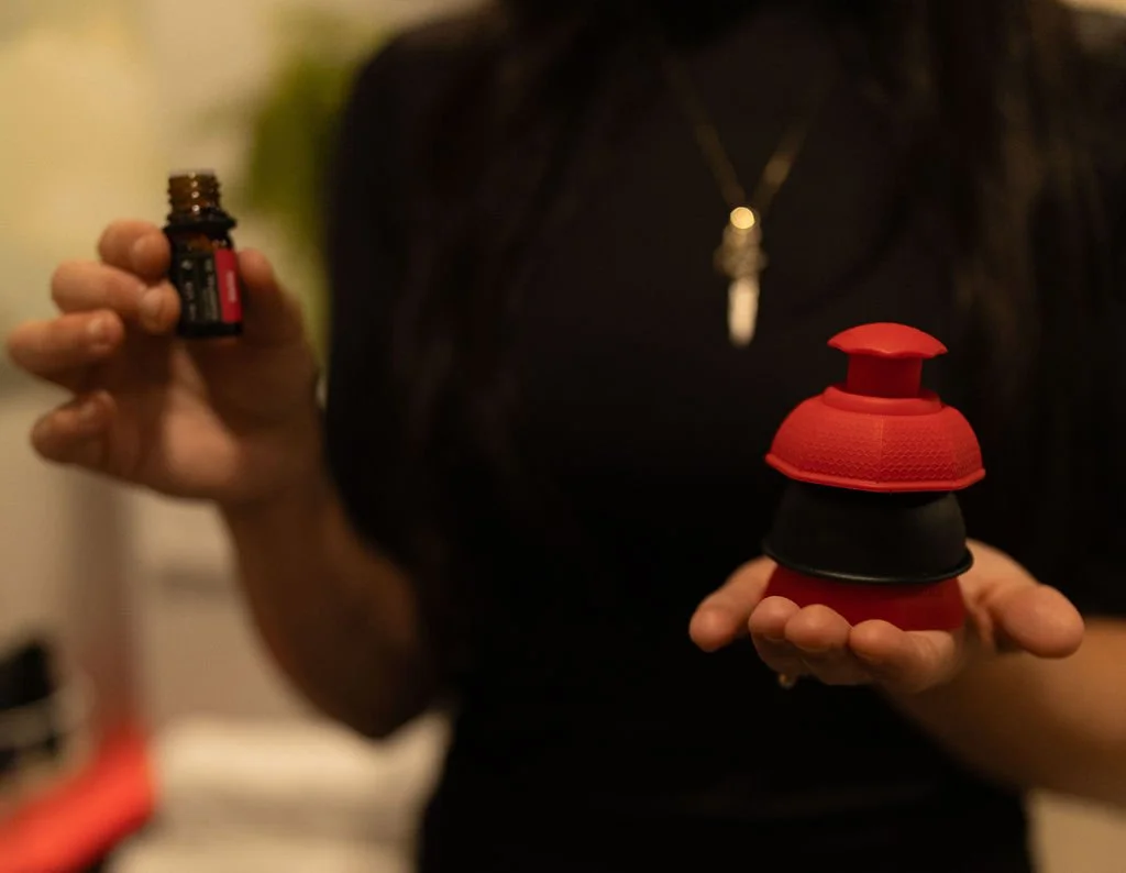 Person holding a small essential oil bottle in one hand and a stack of foam and silicone tampers in the other
