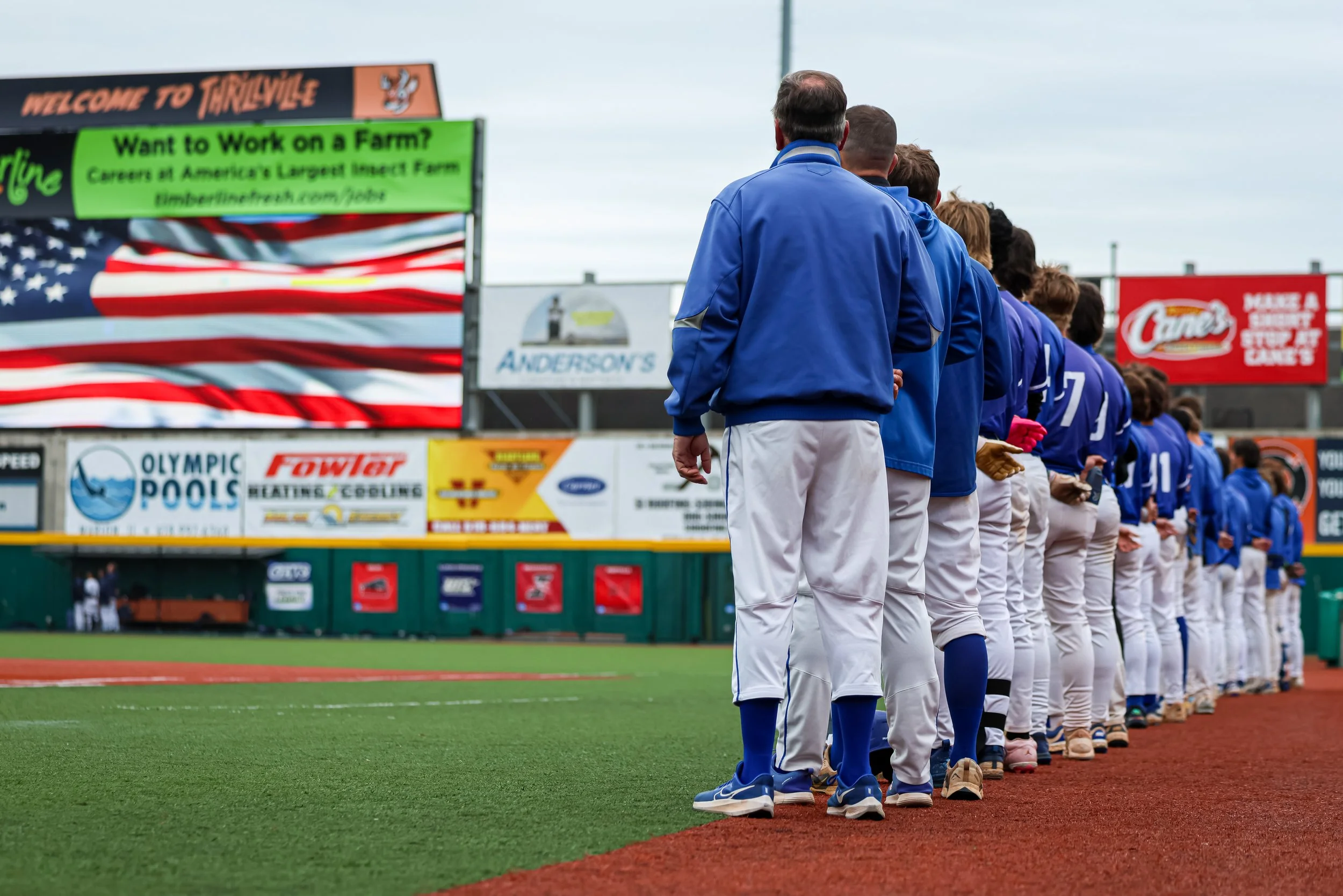 Line of baseball players in blue and white uniforms standing on a baseball field.