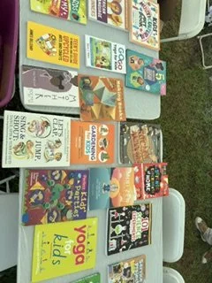 A display of children's books arranged on a table outdoors, featuring colorful covers.