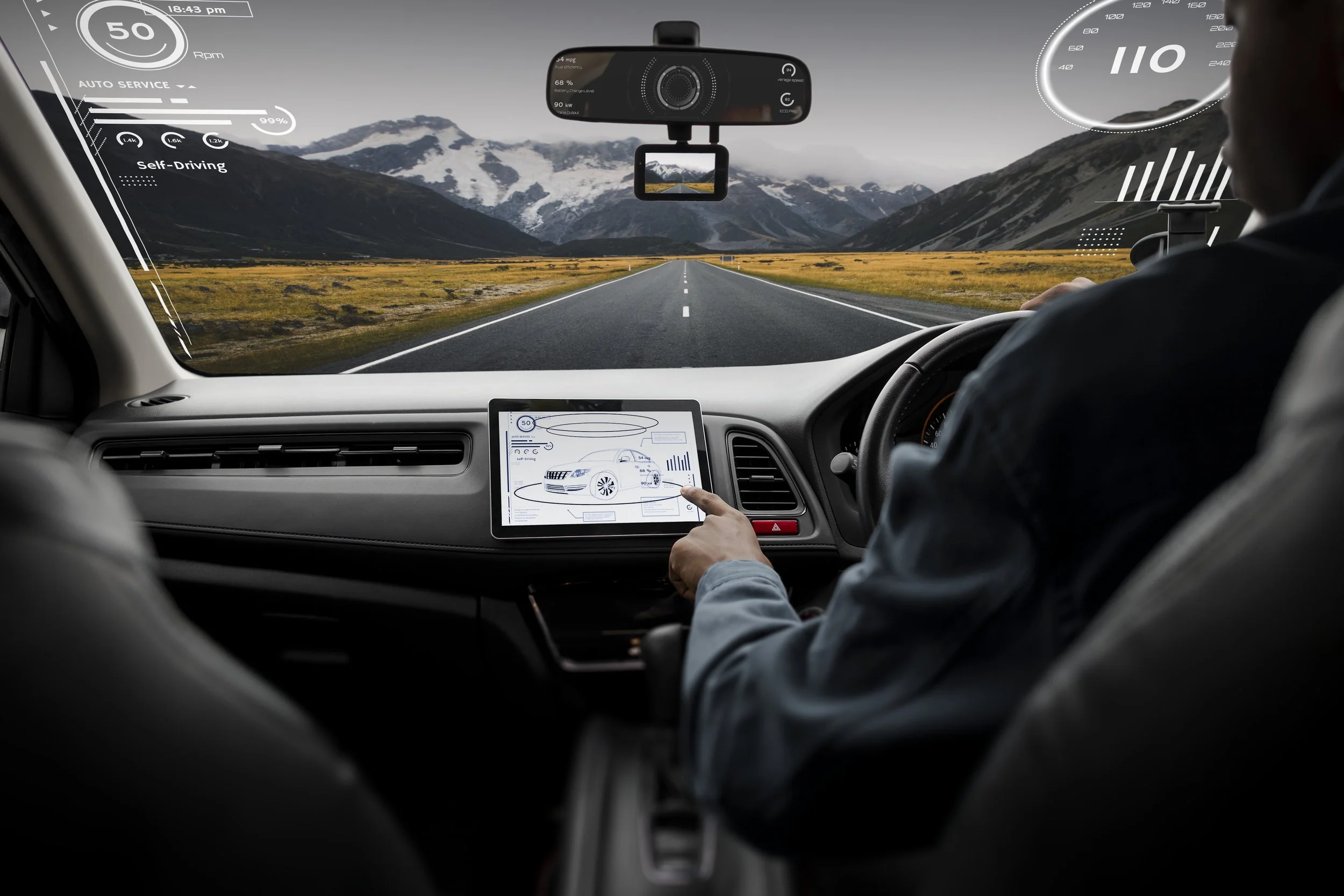 Inside a modern autonomous vehicle with digital interfaces. The driver is managing a touchscreen control panel displaying a car diagram, while additional digital heads-up displays show information like speed, fuel efficiency, and autopilot status. The view outside the windshield shows a long empty road leading towards mountainous terrain with snow-capped peaks under a cloudy sky.