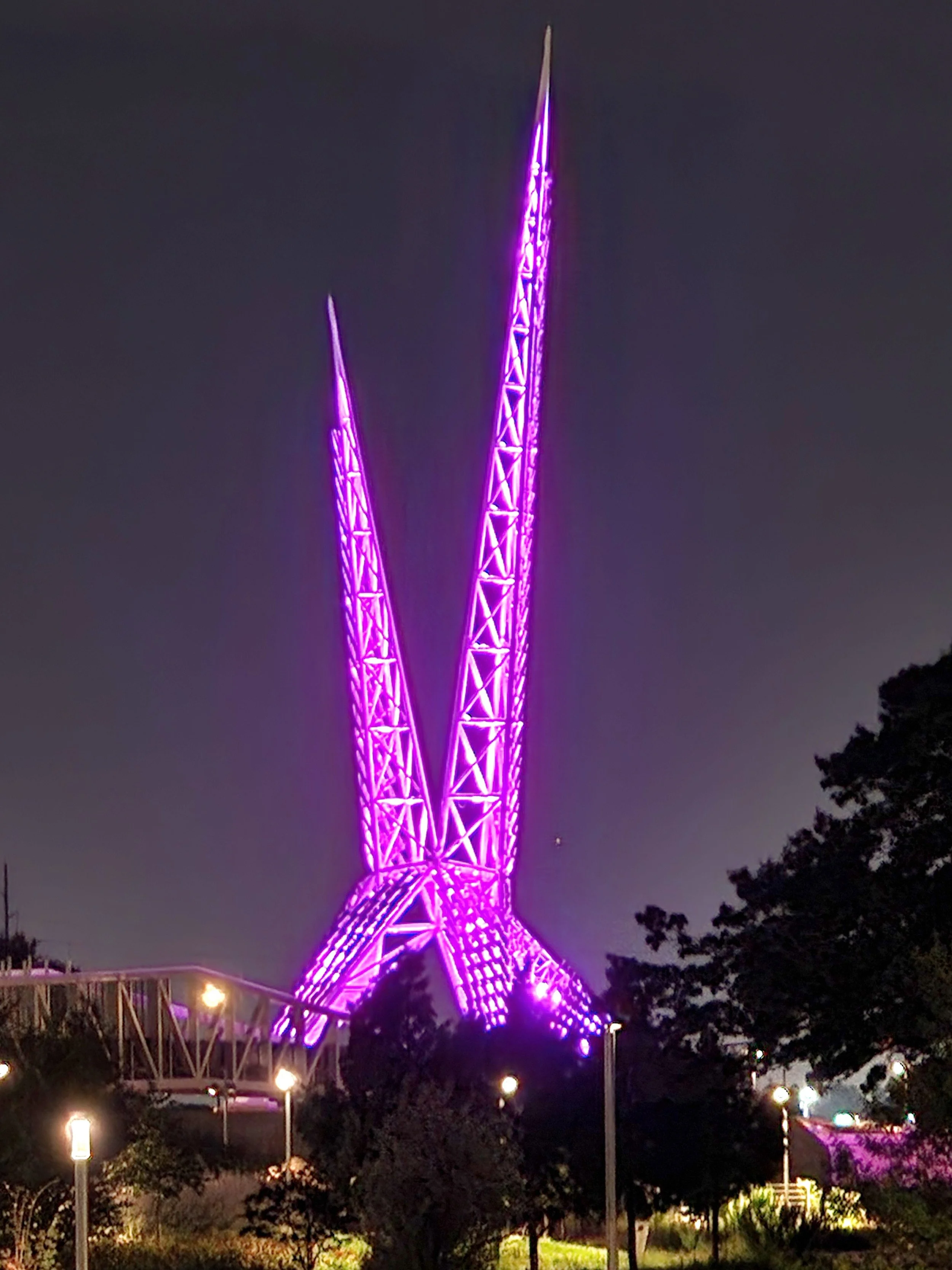 Scissortail Bridge in Oklahoma City lit up purple at night from afar 