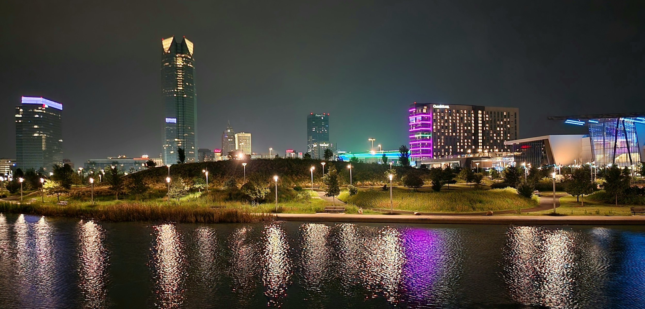 Vibrant Oklahoma City skyline at night reflected in the water from the footbridge over the lake in Scissortail Park