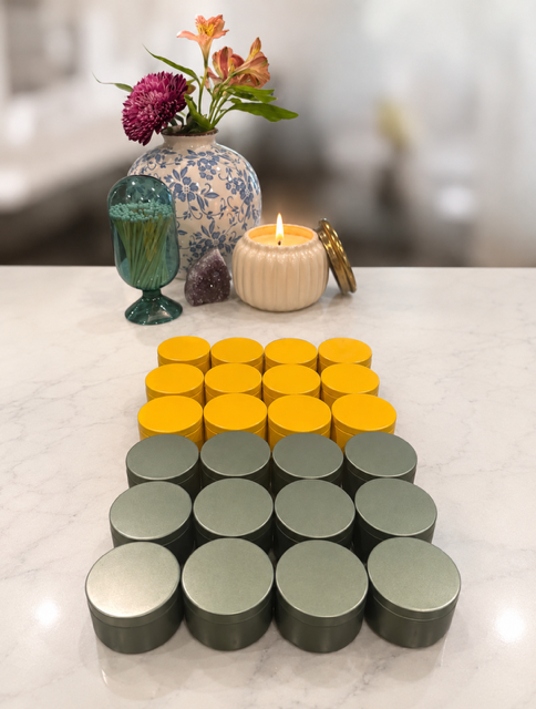 Colorful candles and decorative items on a white marble surface with a flower vase in the background.