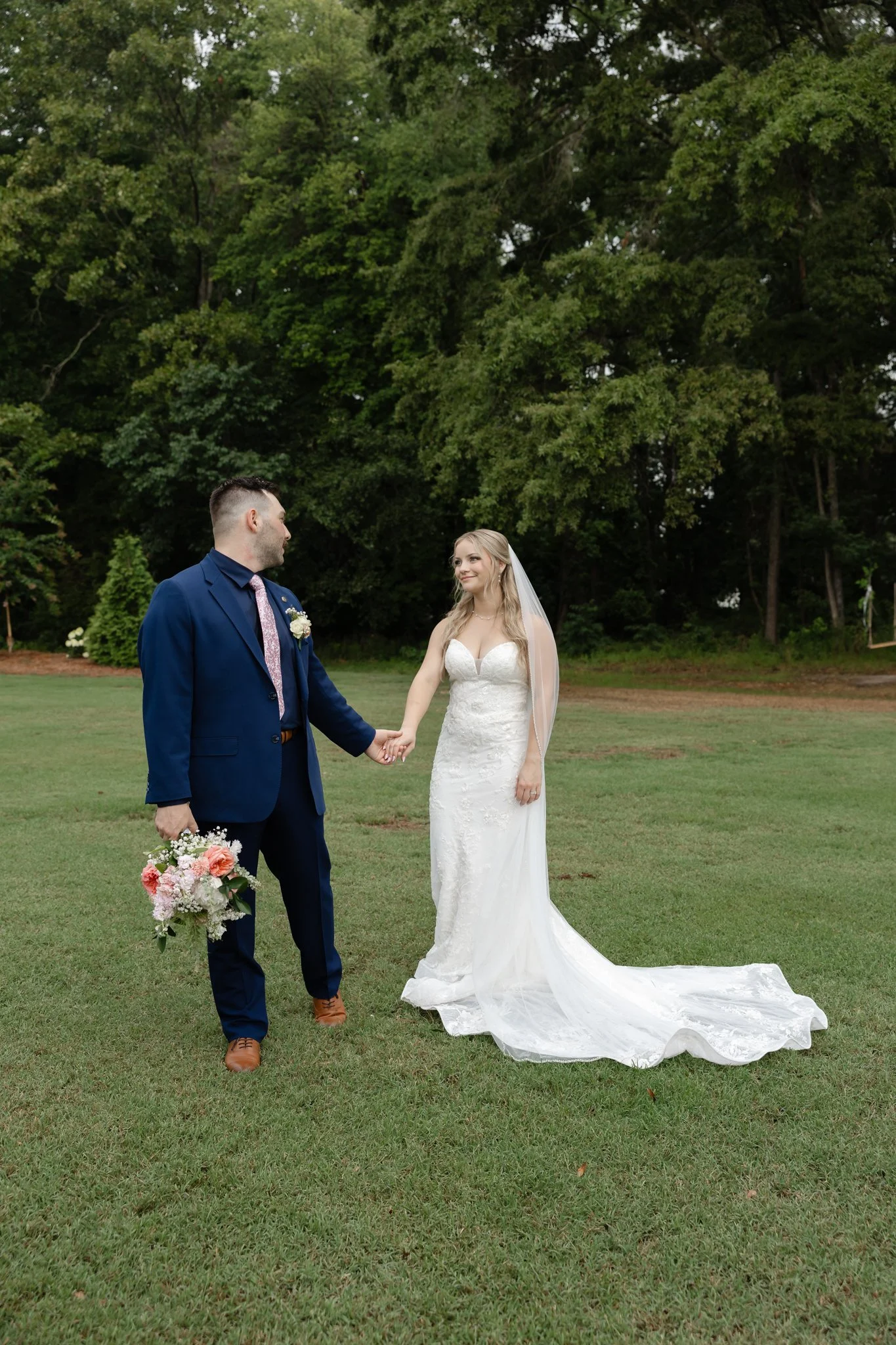 Bride and groom walking hand in hand through the grounds of The Hartwood after their wedding ceremony