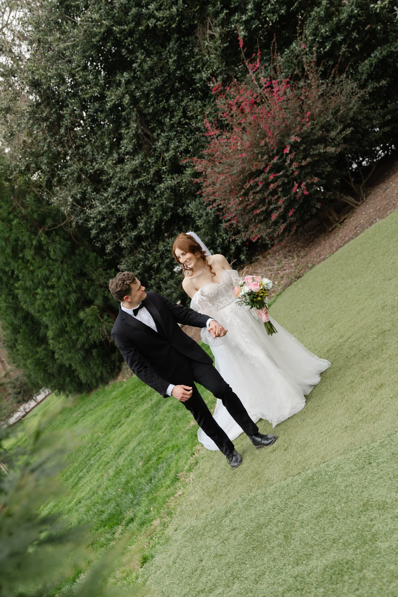 Newly married couple walking hand in hand through the grounds of Highgrove Estate
