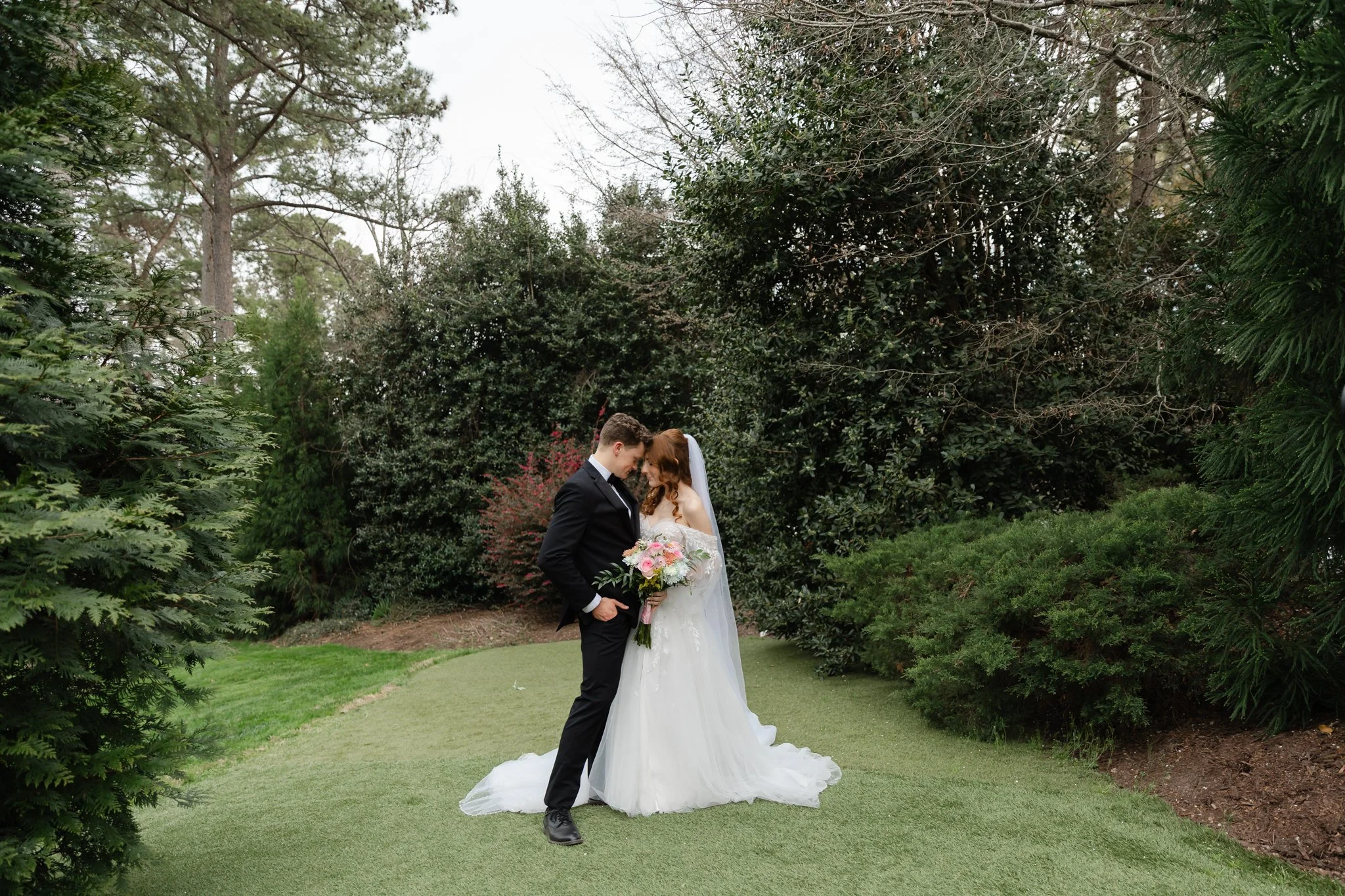 Bride and groom embracing beneath the trees at Highgrove Estate after their wedding ceremony
