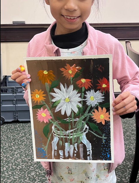 Young girl holding a painted picture of colorful flowers in a glass jar.