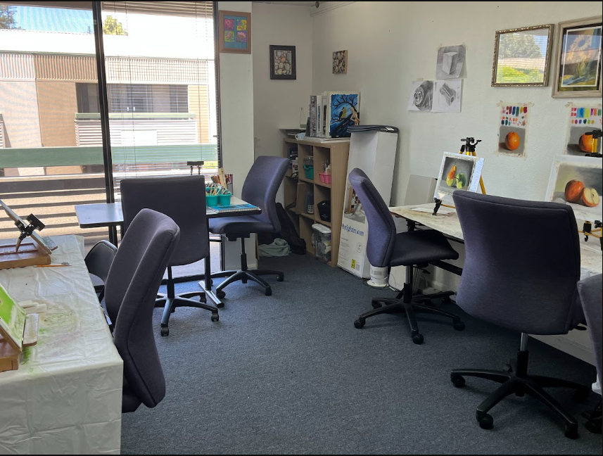 Art classroom with tables, chairs, artwork, and art supplies
