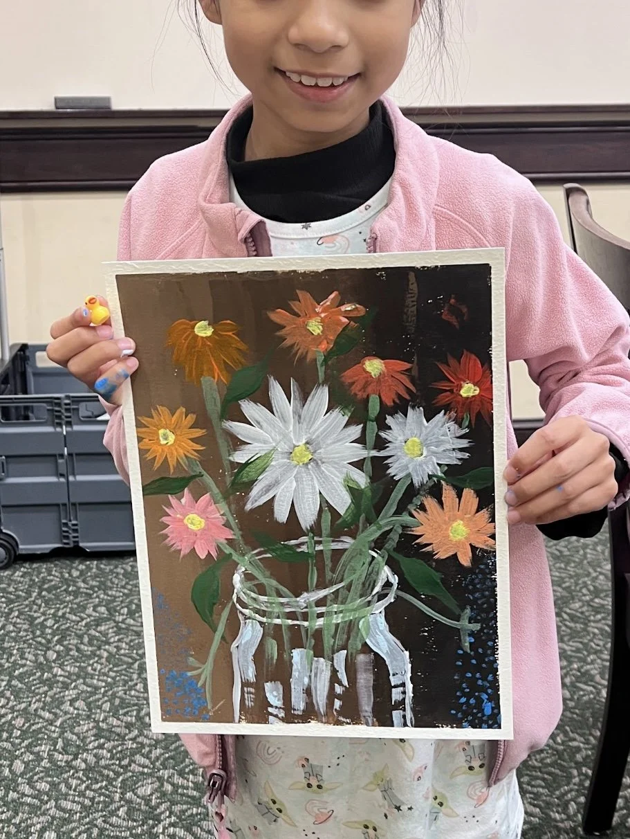 A young girl with a pink jacket holding a colorful painting of a flower bouquet in a jar.