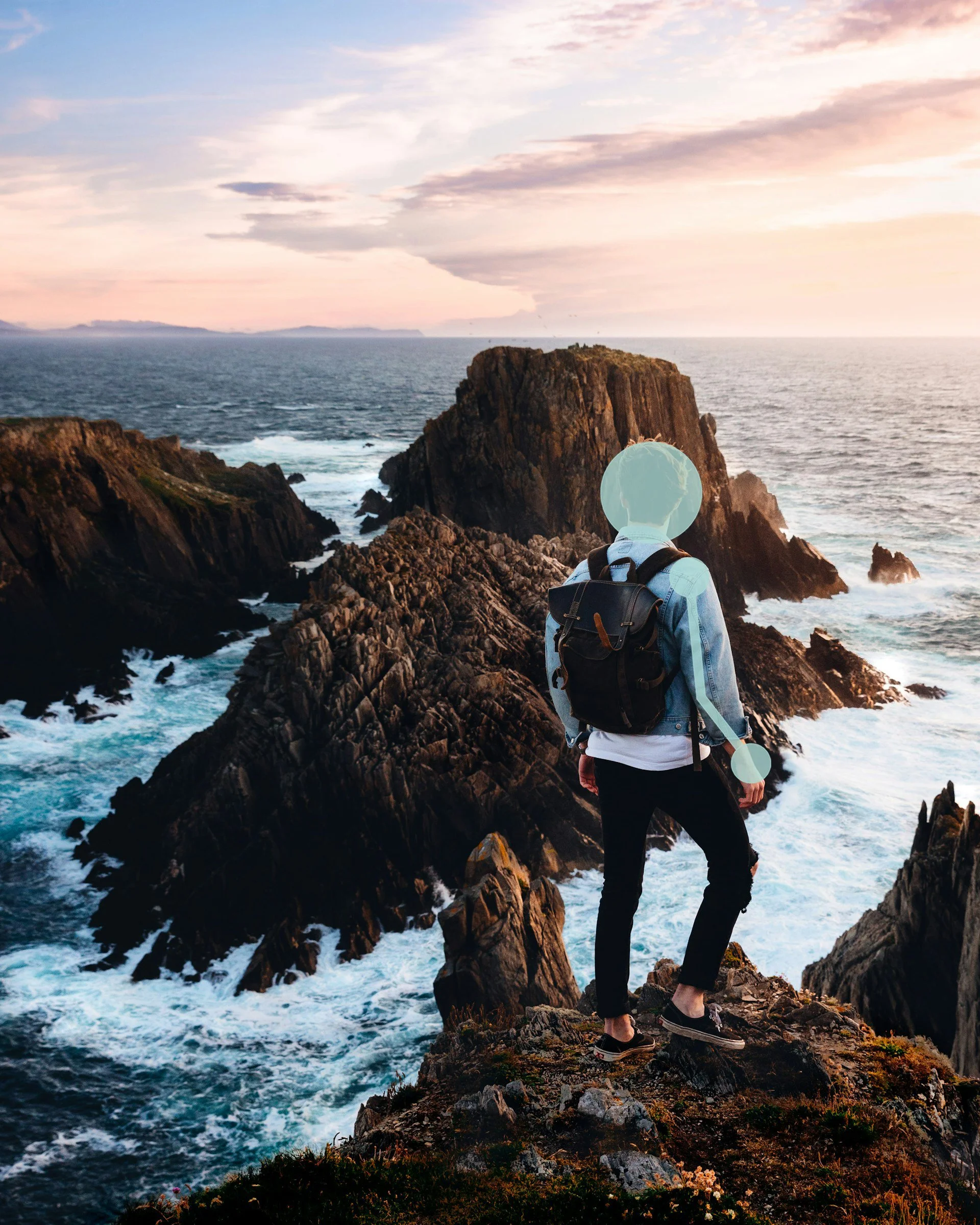 A person with a backpack and hiking shoes standing on rocks by the ocean, looking out at the sunset with clouds, a large rock formation, and small islands in the distance.
