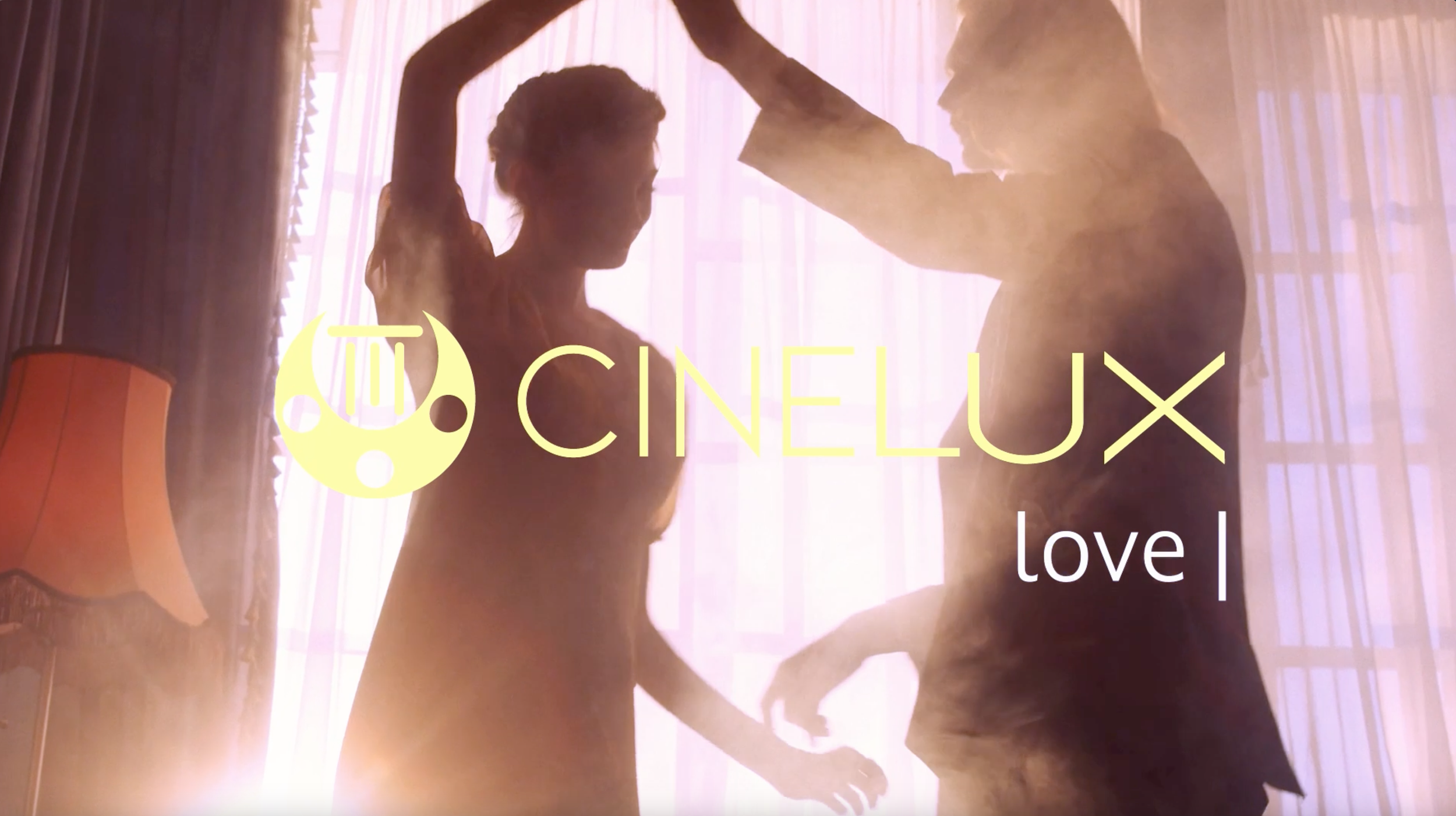 Silhouettes of a man and a woman in a romantic pose with their foreheads touching, backlit by soft pink and purple lighting, with a curtain and a lamp in the background.