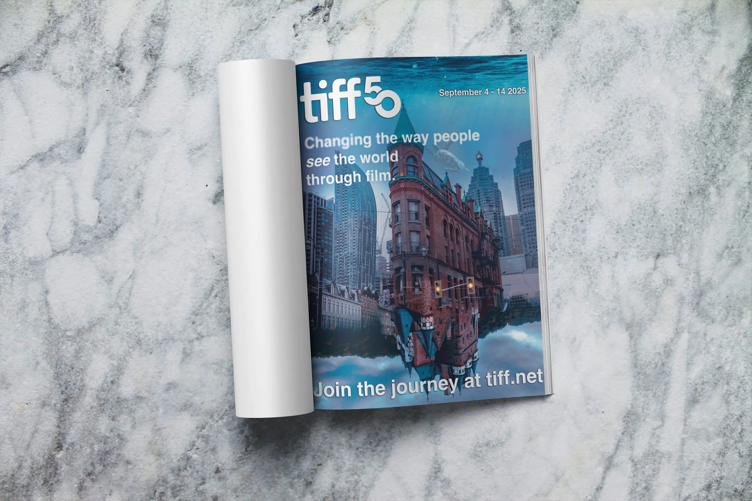 Open magazine on a marble surface showcasing an article about TIFF Toronto International Film Festival, with the festival date September 4-14, 2025, and a cityscape with buildings and a blue sky.