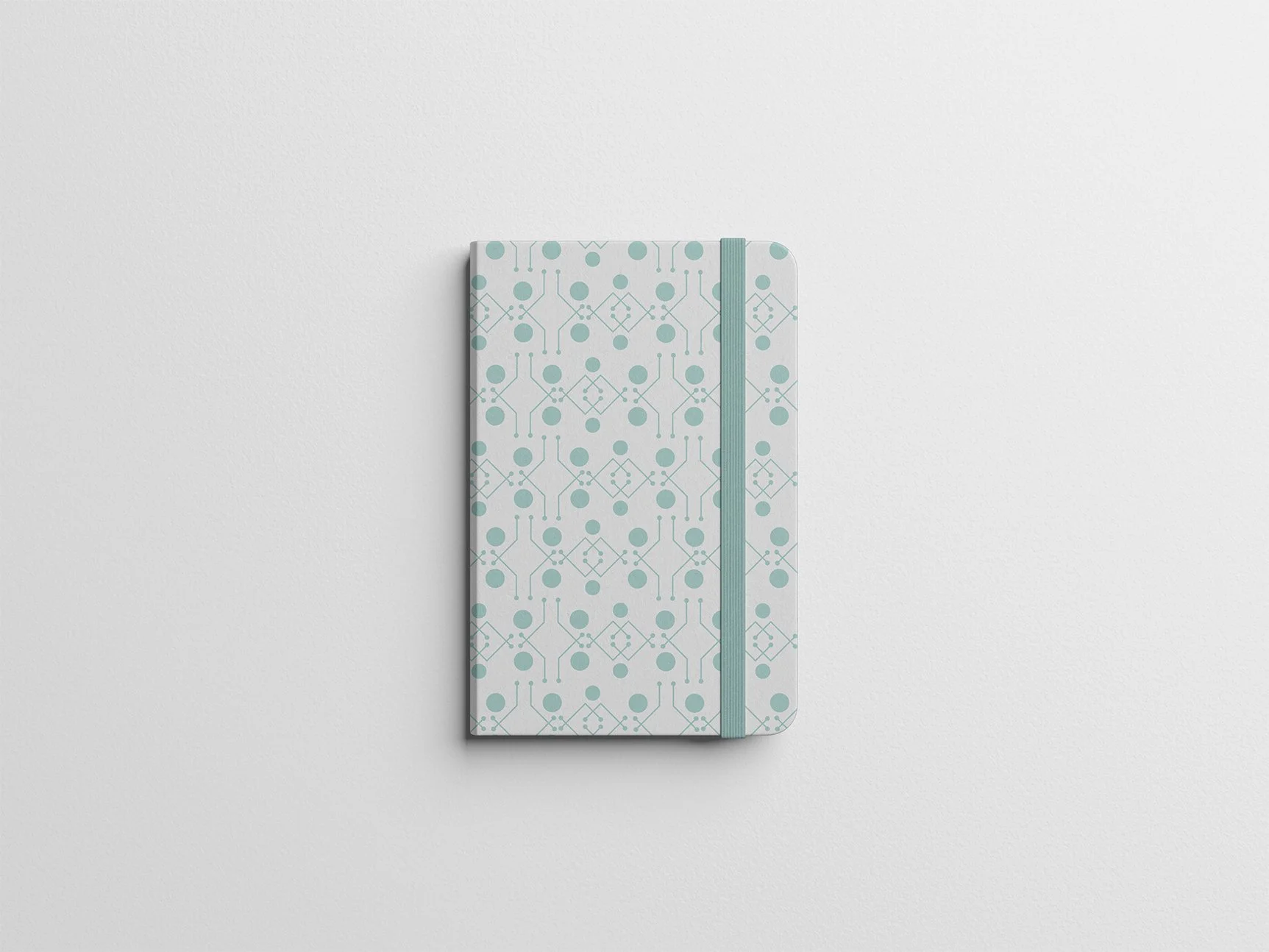 A closed, hardcover spiral notebook with a geometric pattern in blue and white, secured shut with a light blue elastic band, placed on a white surface.