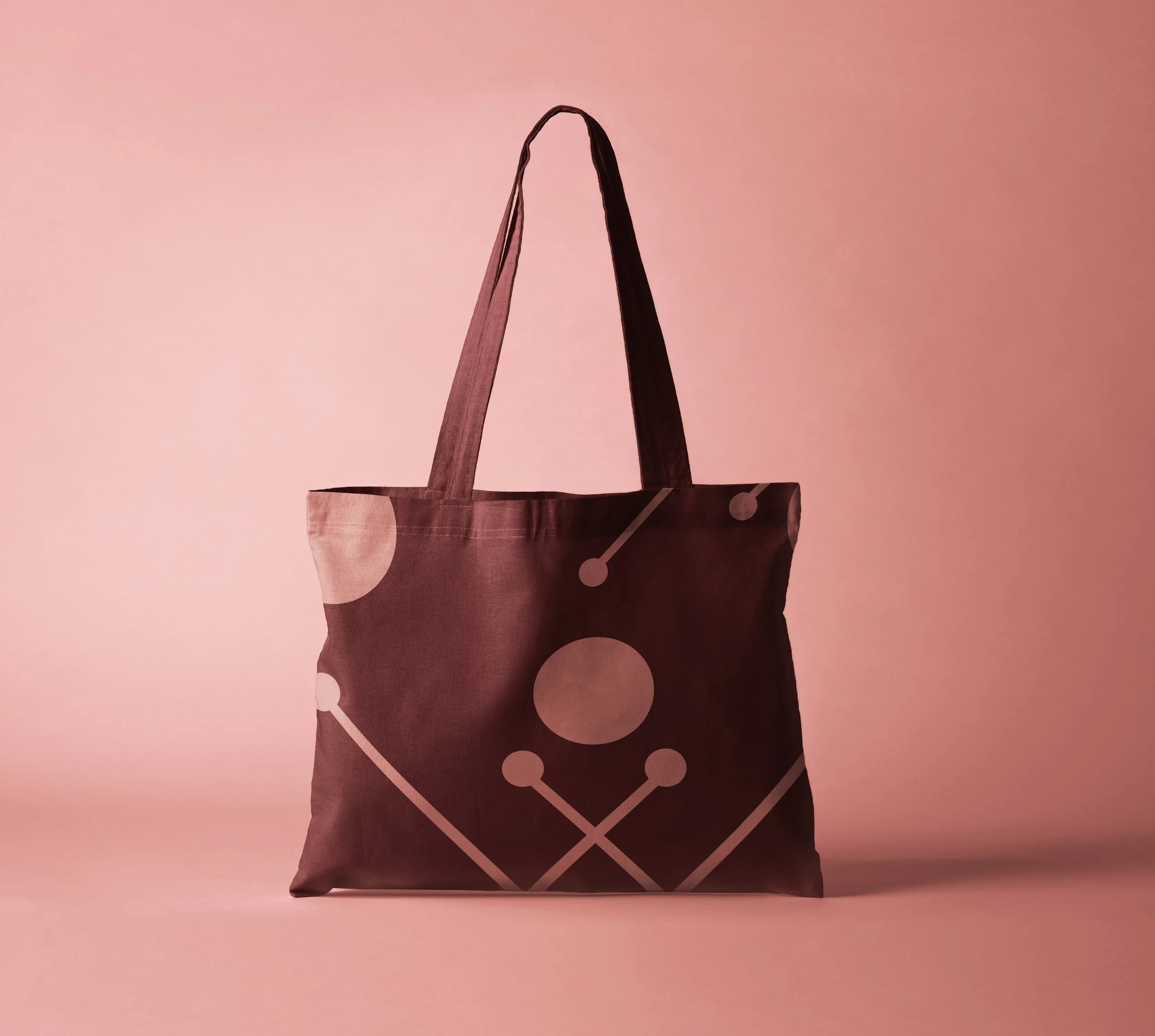 A pink tote bag with a white geometric dot and line pattern, placed against a pink background.