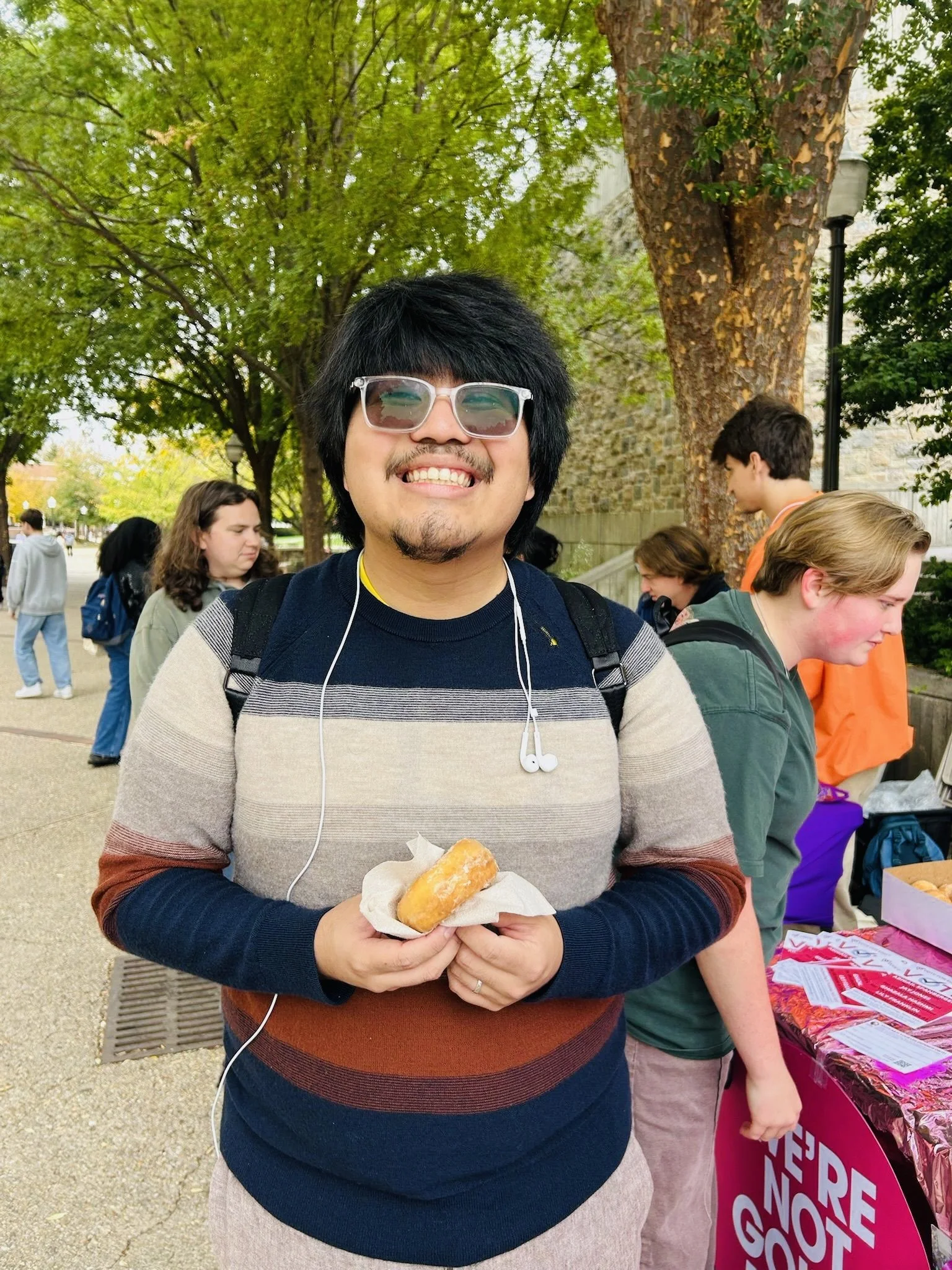 Person smiling with a donut at a tabling event