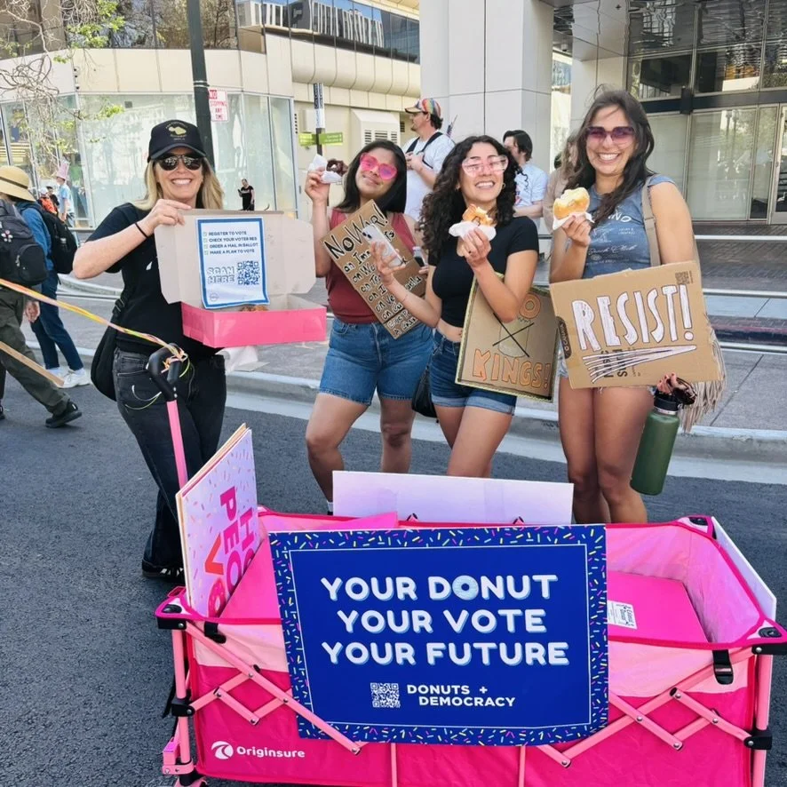Four people with signs and a donut wagon