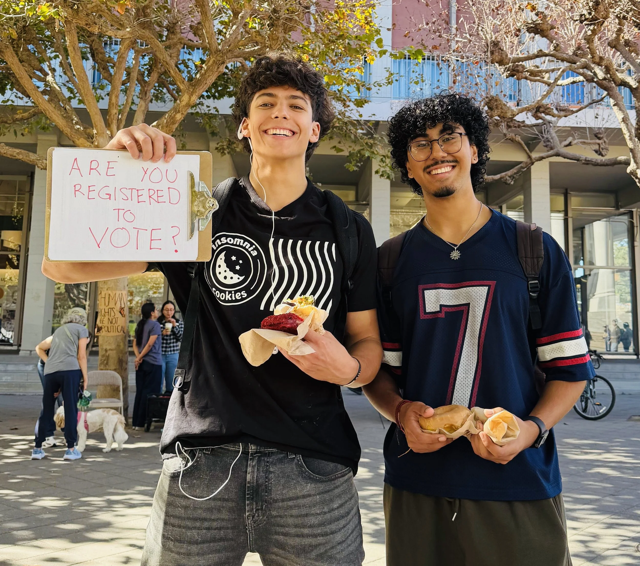 Two people with donuts and a clipboard that says "are you registered to vote?"