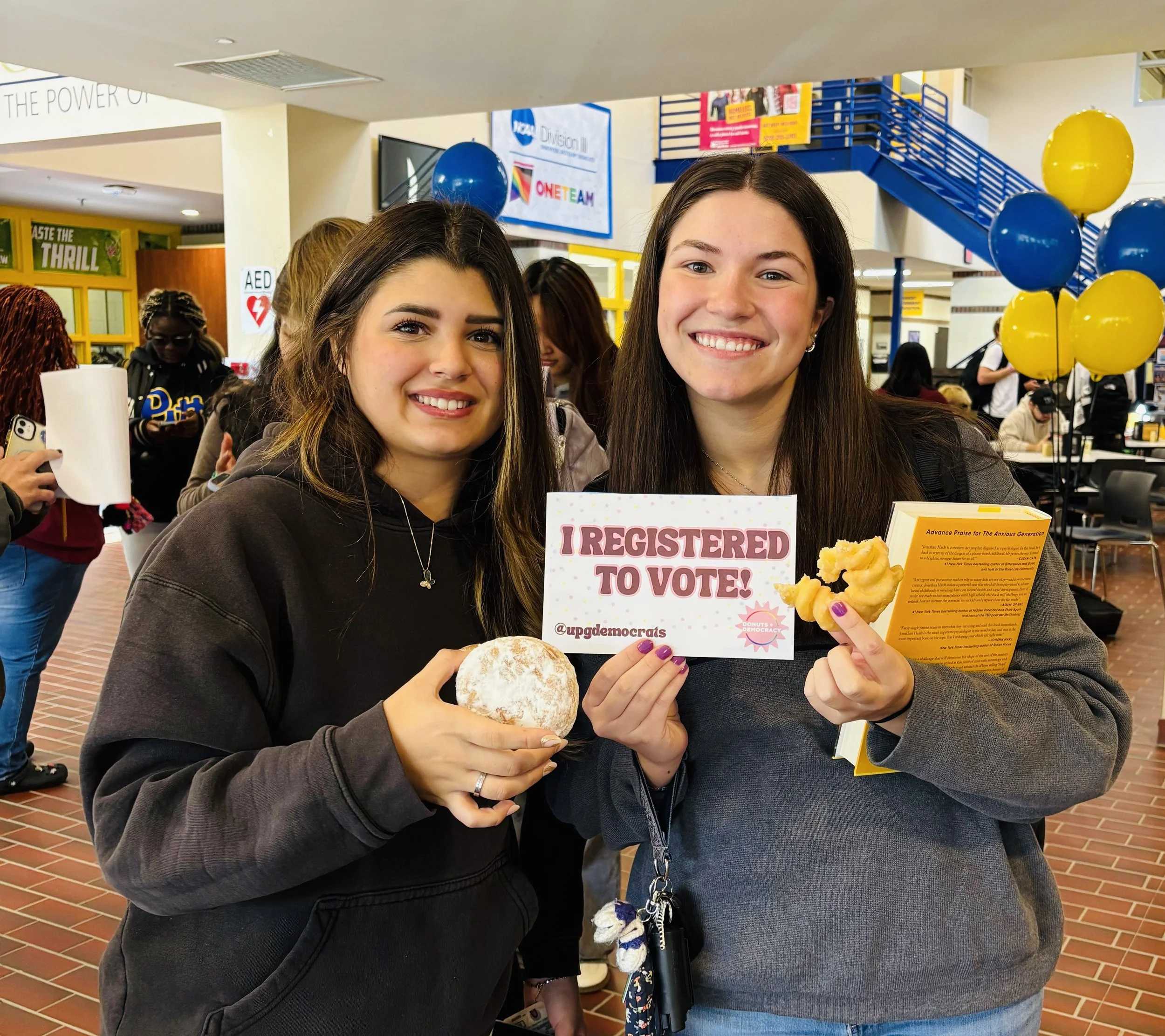 Two people with donuts and a sticker that says "I registered to vote"