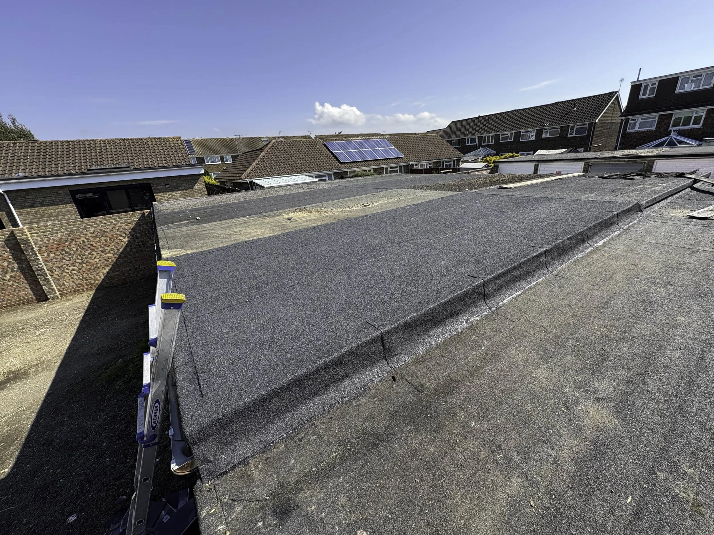 View of rooftops with solar panels under a clear blue sky.