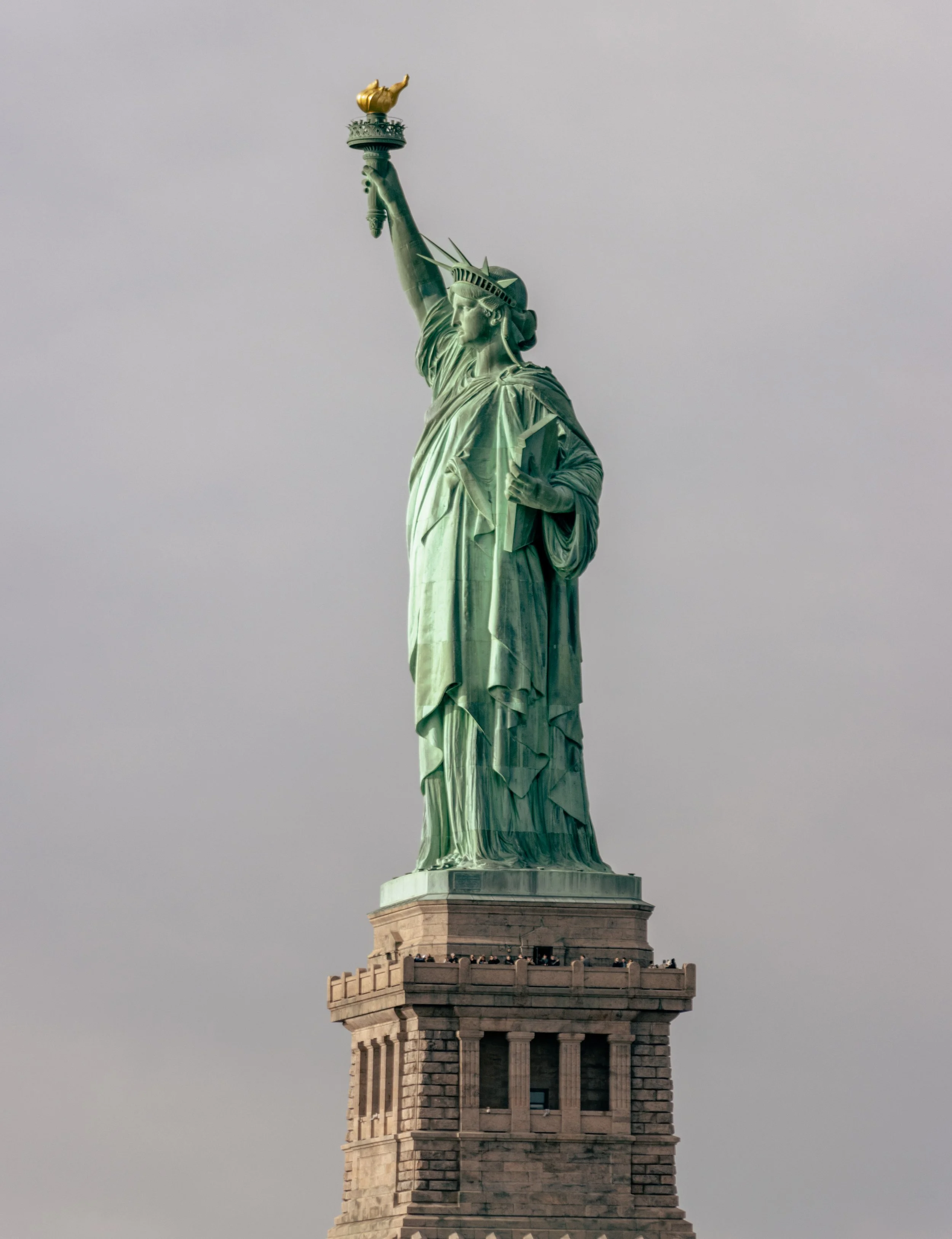 The Statue of Liberty standing on its pedestal against a gray sky.