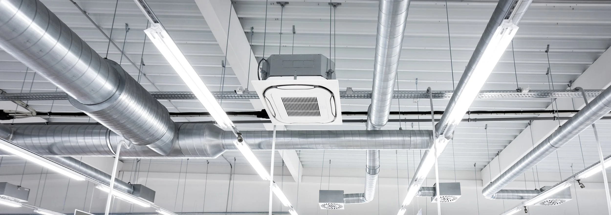 Ceiling with HVAC ductwork & ventilation units in a commercial building.