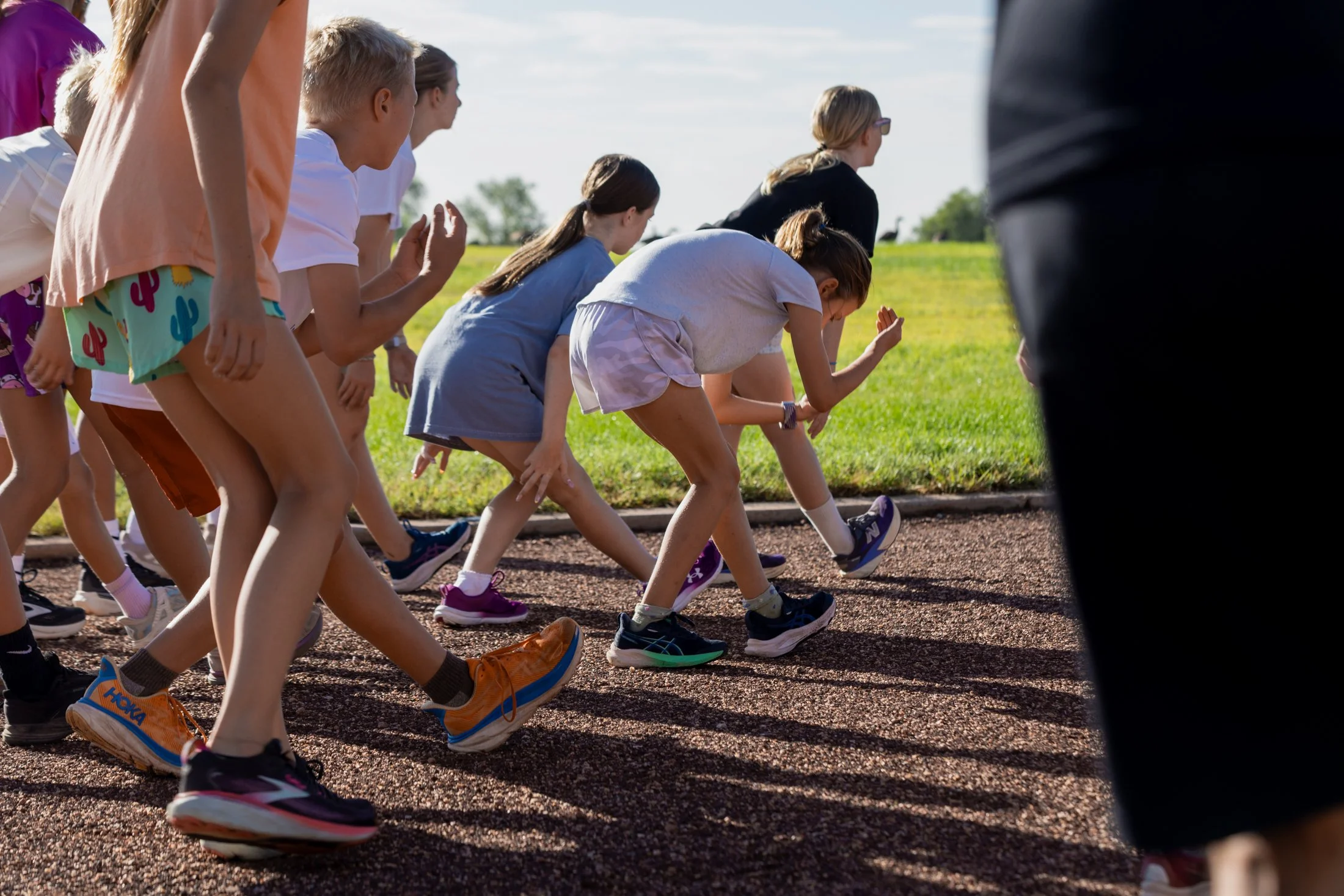 Children at the starting line of a race on a track outdoors on a sunny day.