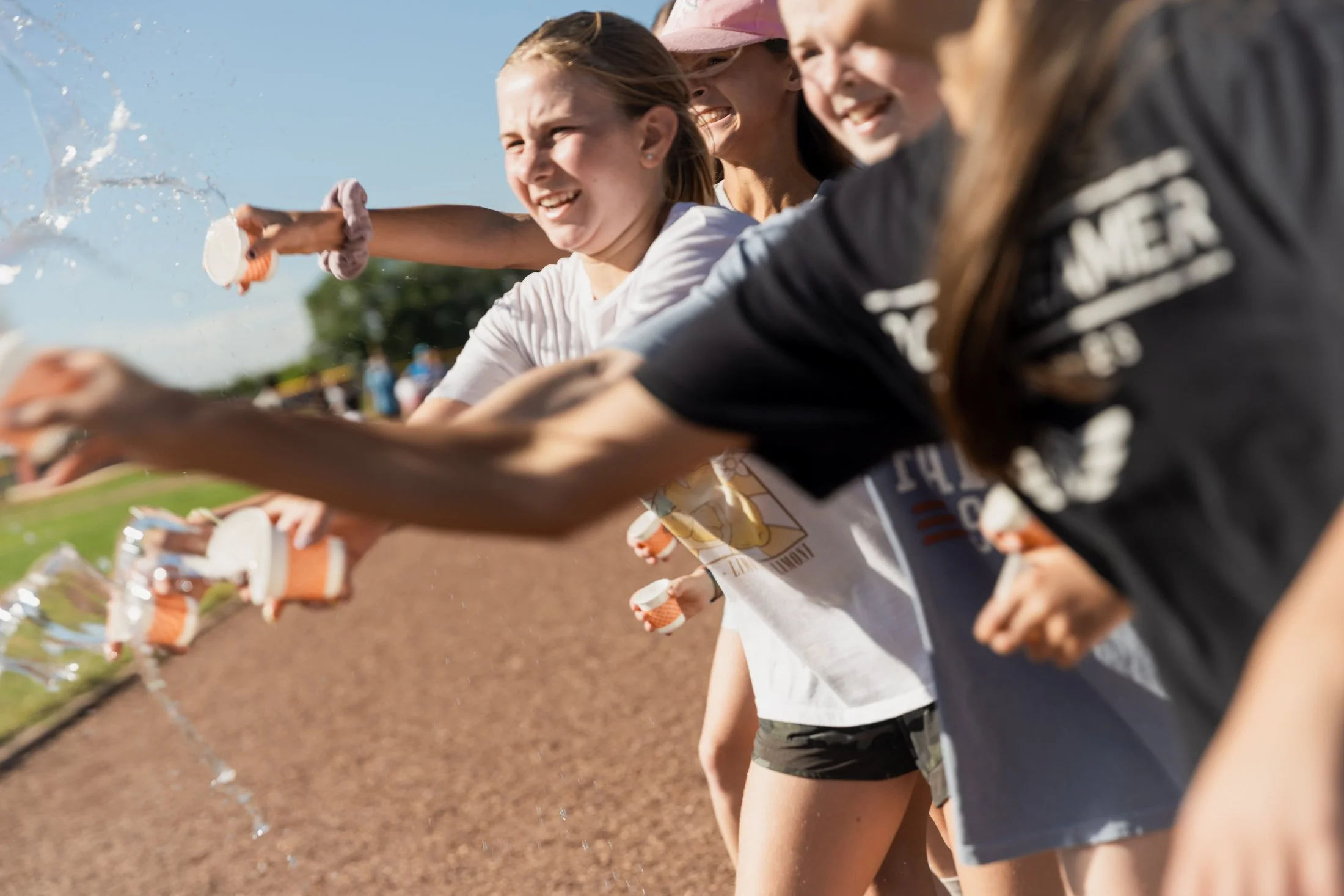 Teenagers participating in a relay race at an outdoor track and field event, passing batons to each other.