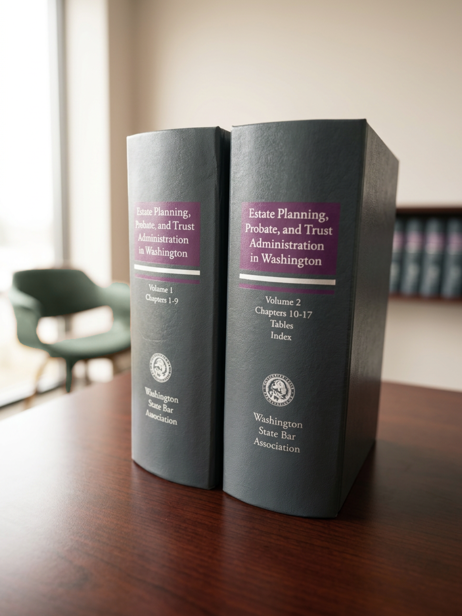 Two books titled 'Estate Planning, Probate, and Trust Administration in Washington', volume 1 and volume 2, standing upright on a wooden table with a blurred chair in the background.