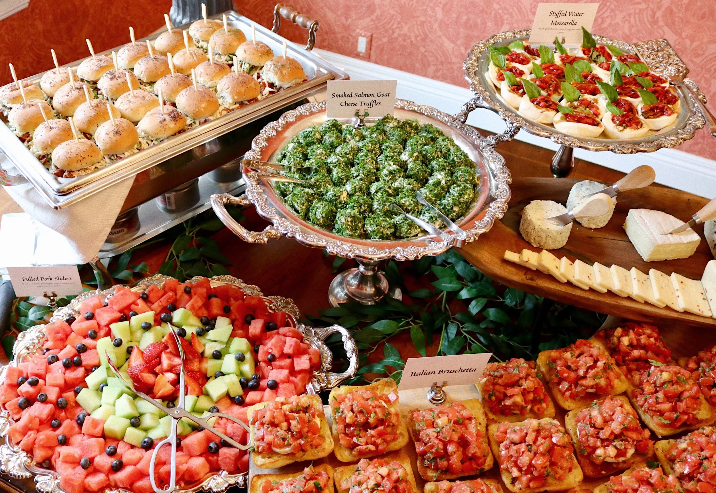 Smoked salmon goat cheese truffles rolled in poppy seeds, toasted sesame seeds, dried garlic, dried onion, and sea salt, surrounded by pulled pork sliders, stuffed water mozzarella, bruschetta, assorted fruits, and cheeses, prepared by Silver Platter