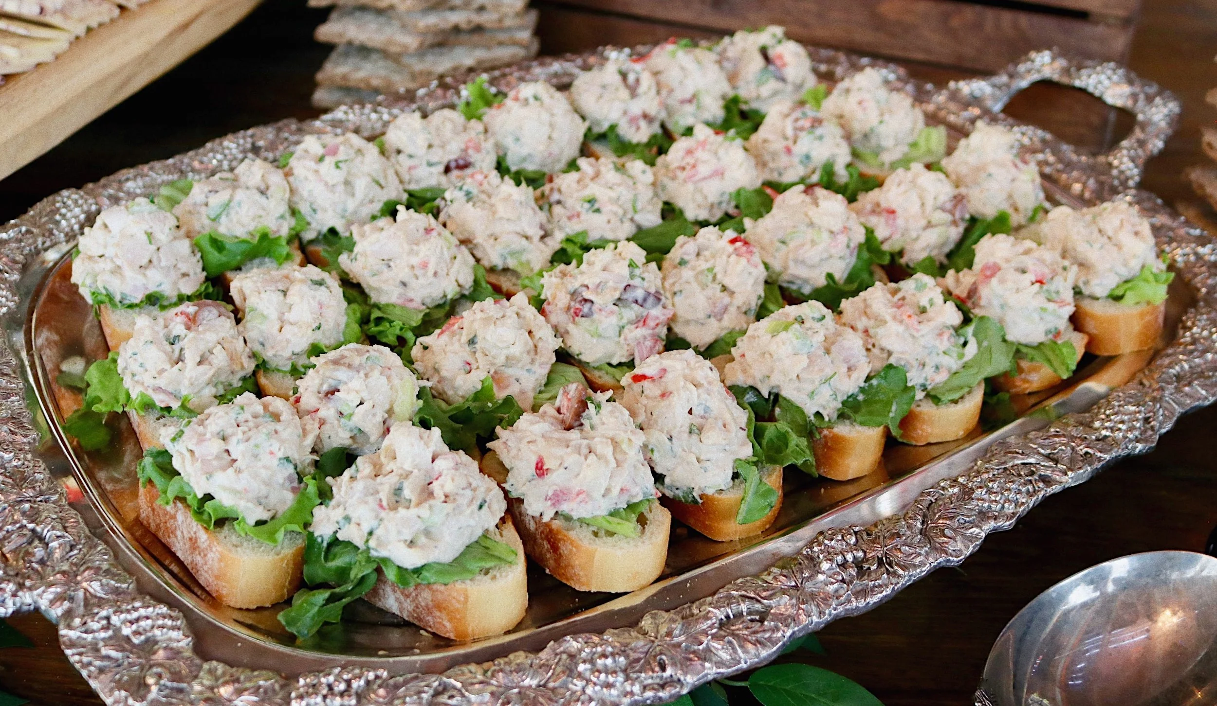 Mini smoked chicken salad sandwiches with red and green peppers, celery, shallots, and fresh herbs on sliced baguette, prepared by Silver Platter Catering