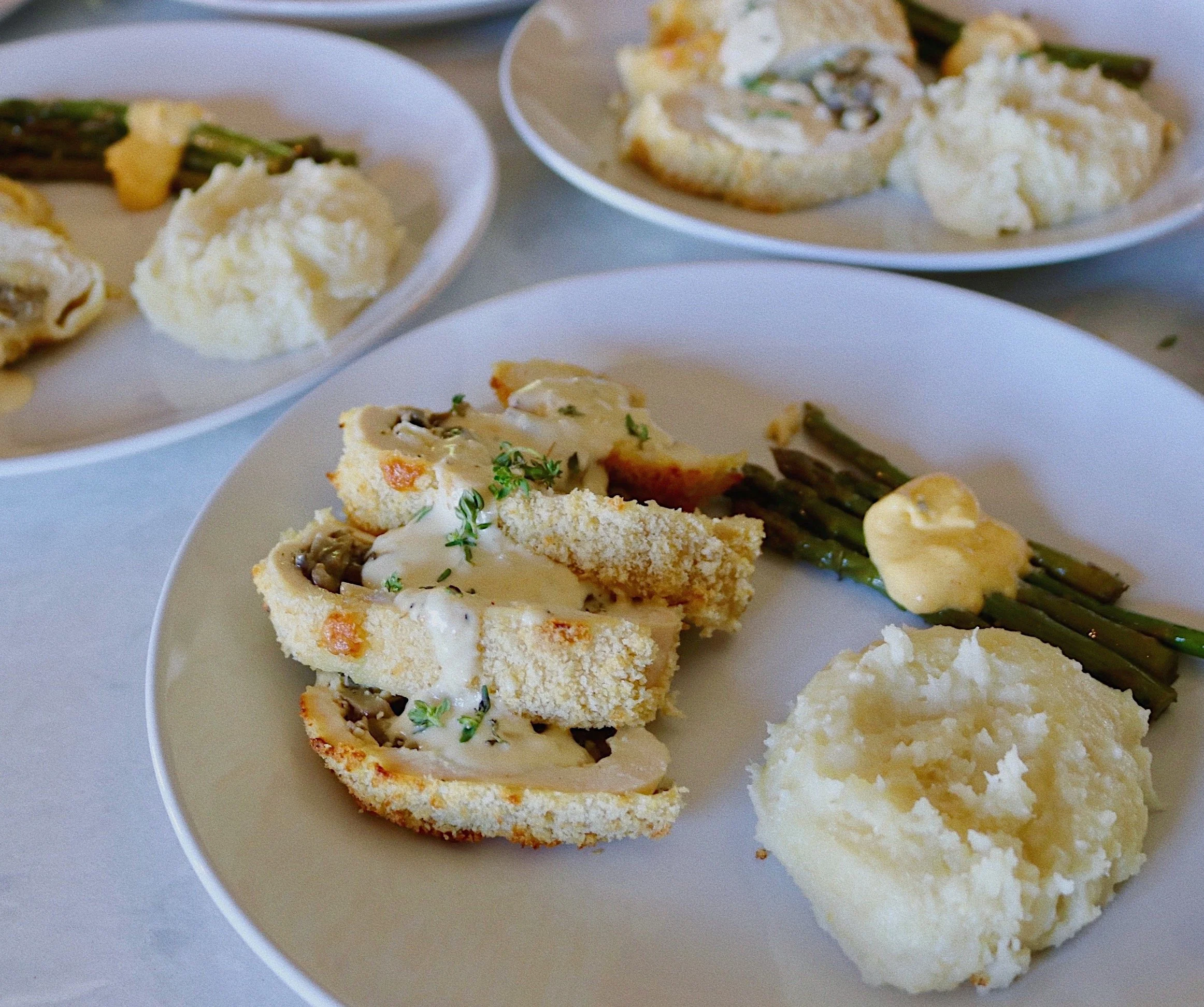 Stuffed chicken served with a side of mashed potatoes and asparagus, prepared and catered by Silver Platter Catering